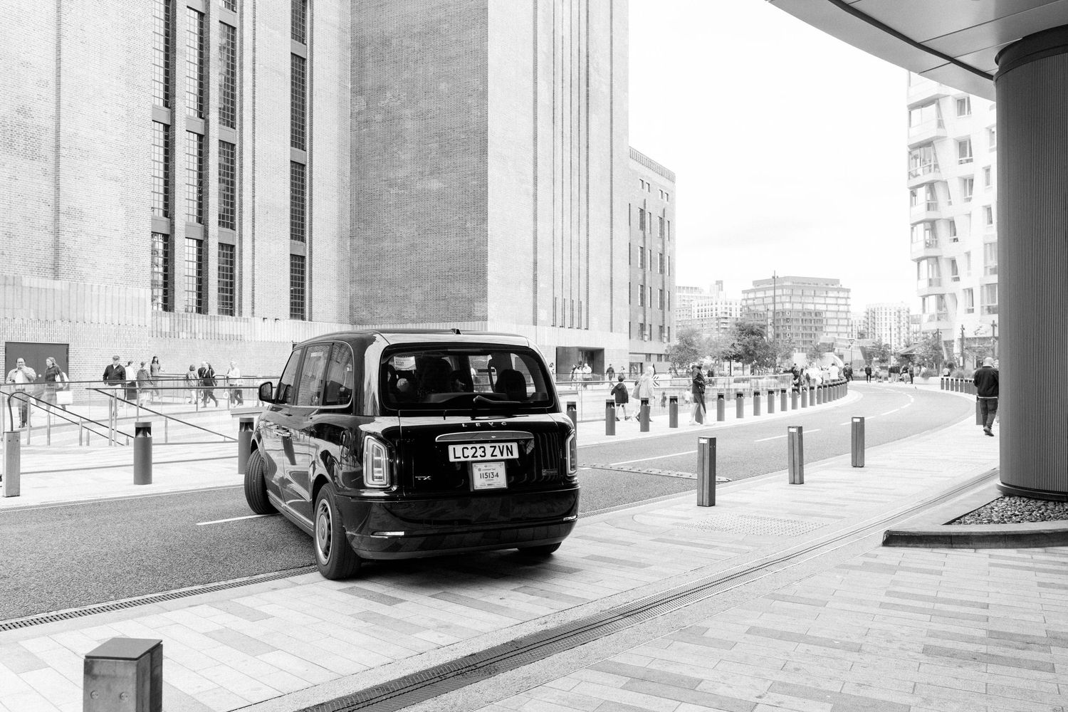 Urban street scene with modern buildings and parked cars in black and white.