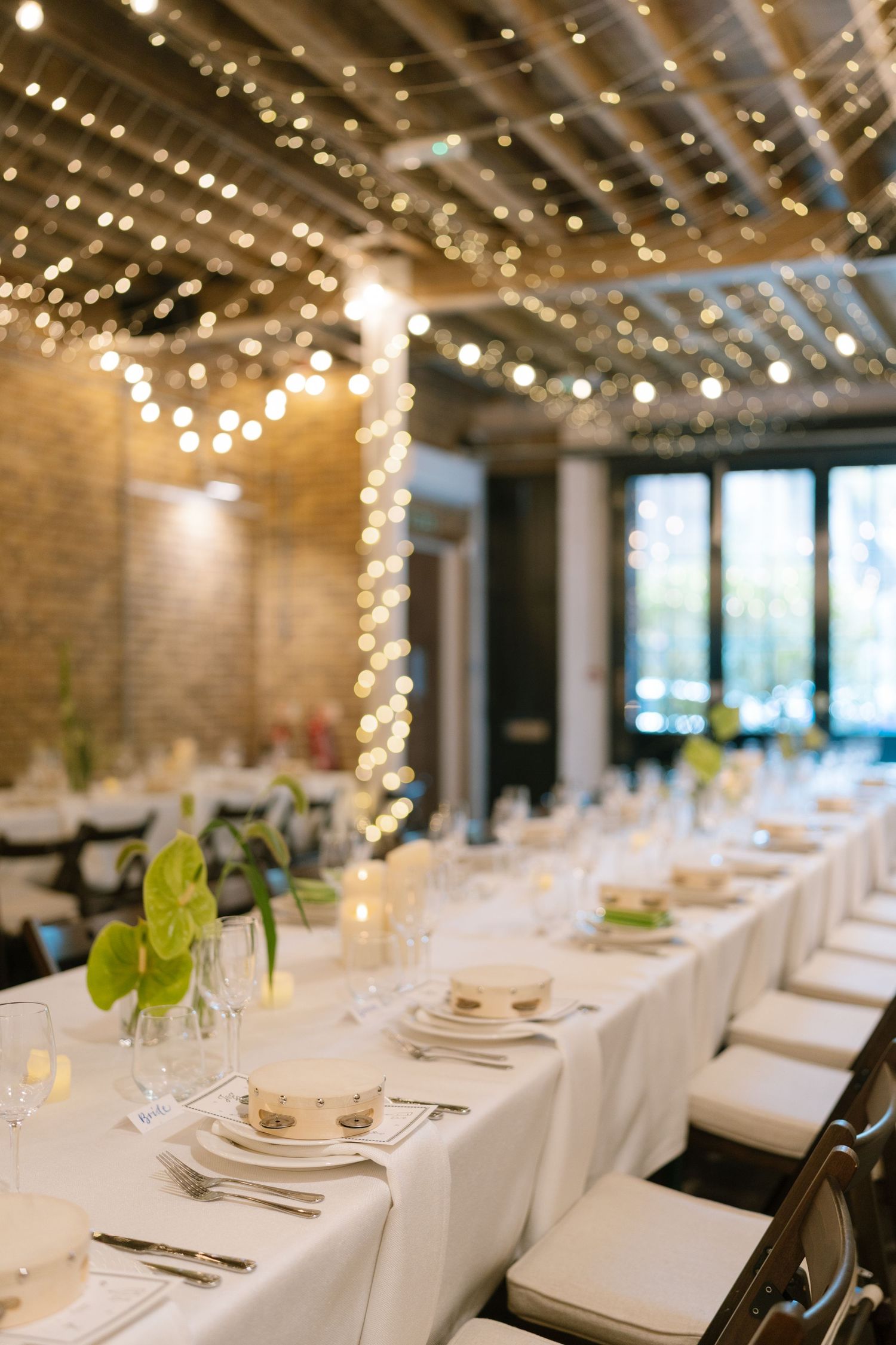 Wedding reception venue with string lights and white table settings creating an elegant atmosphere.