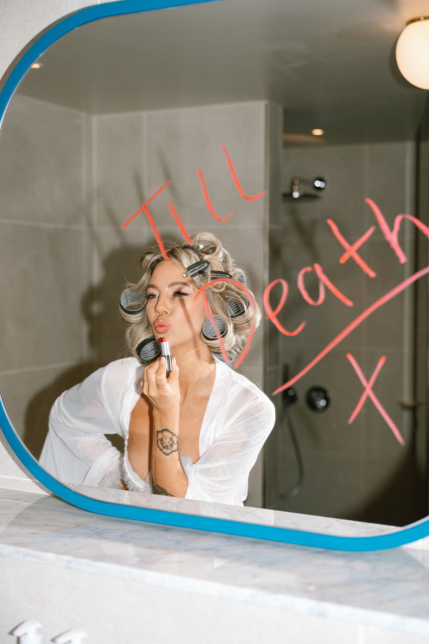 Getting ready scene with hair in curlers reflected in a mirror with blue trim.