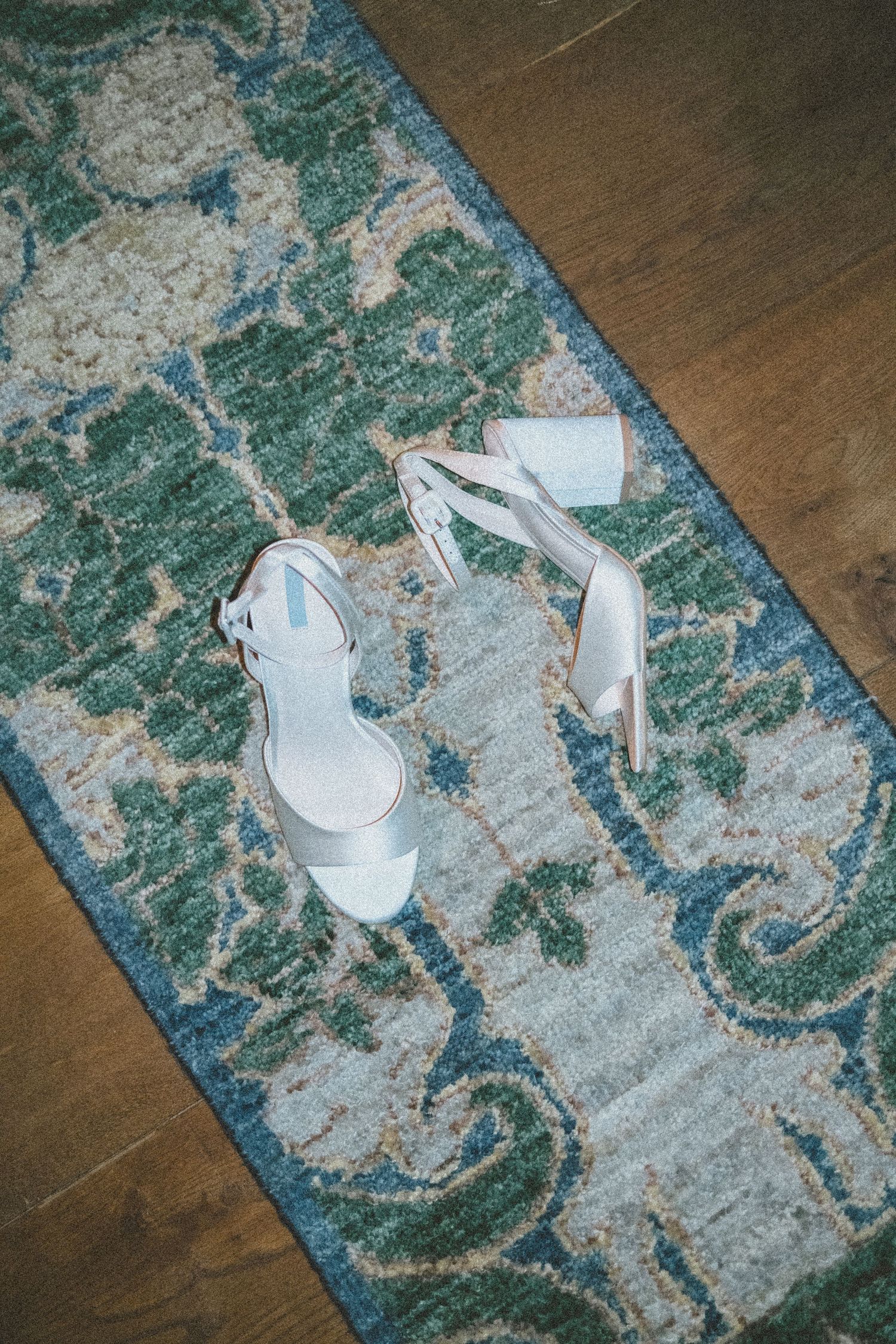 White high heel sandals placed on a blue and gray patterned area rug showing multiple angles and positions.