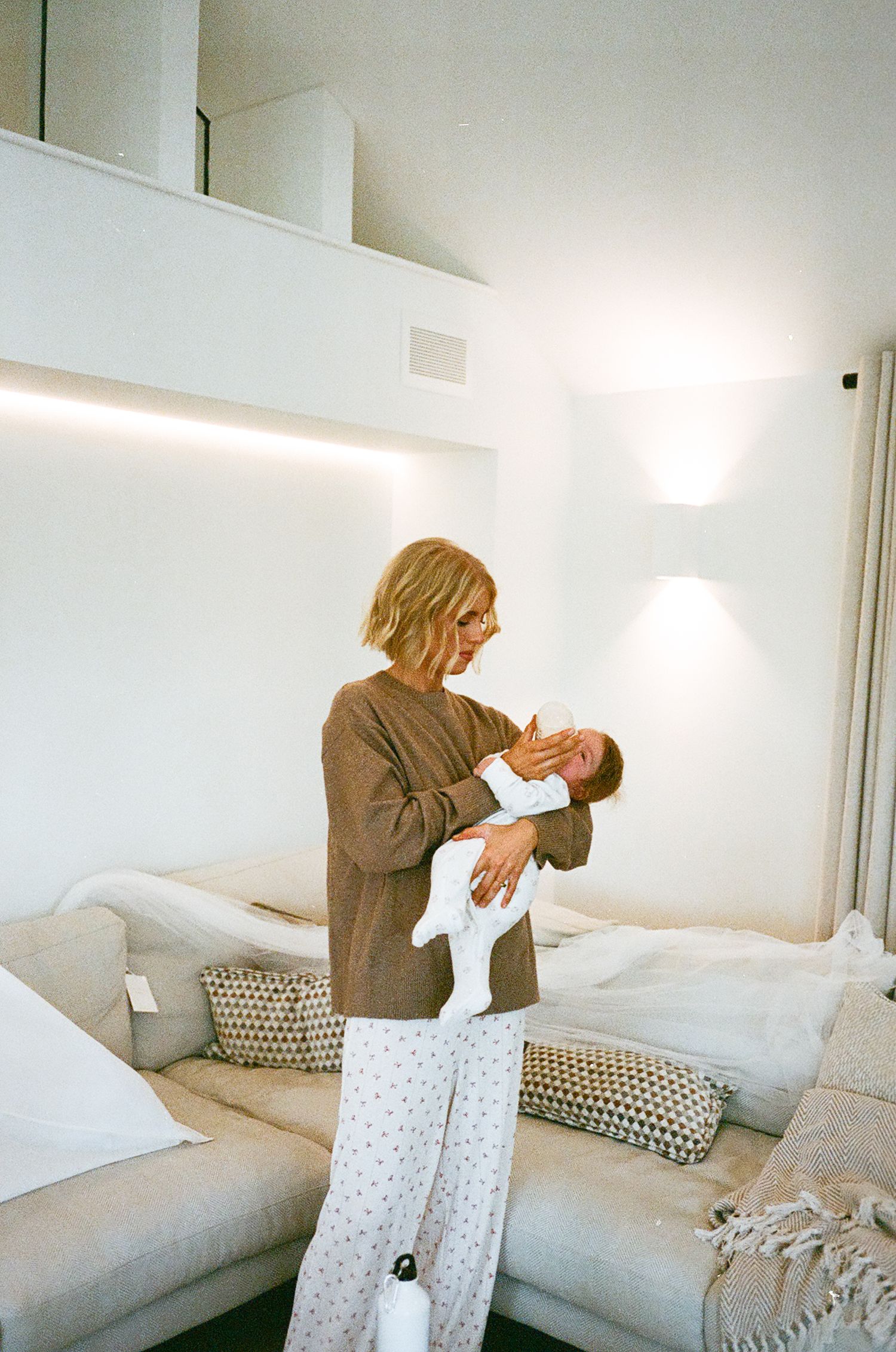 A sequence of photos showing someone sitting on a white couch holding and playing with a small baby.