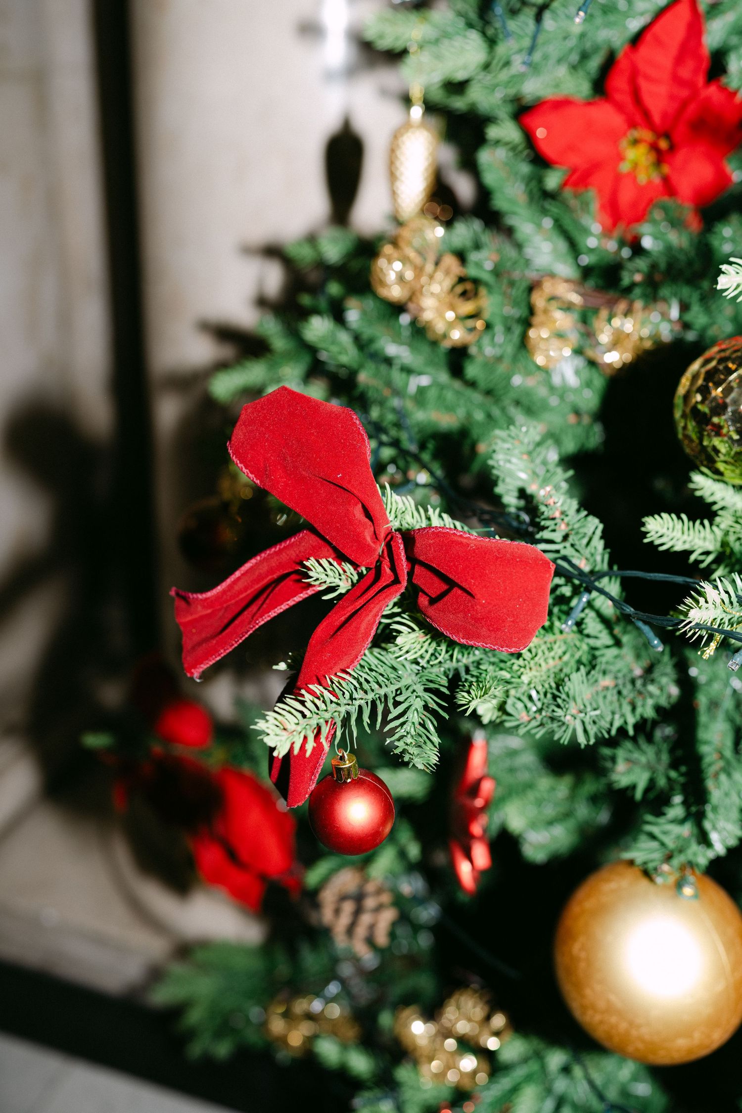 Christmas tree decorated with red poinsettias and gold ornaments.