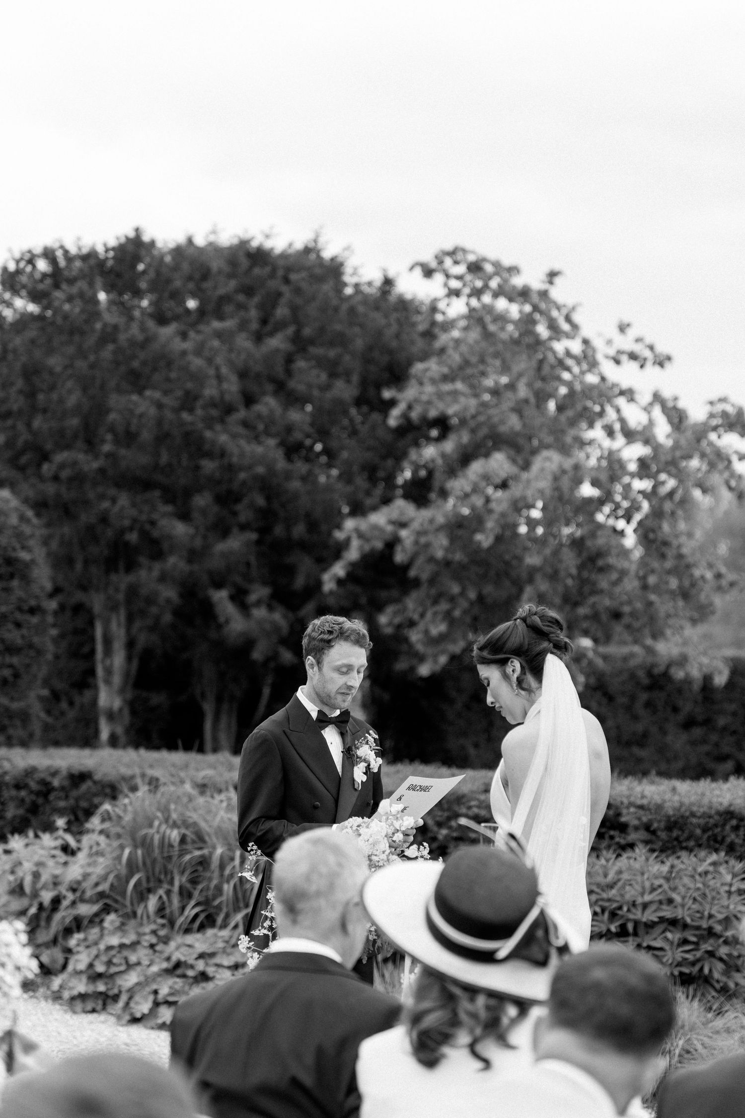 Black and white image of bride and groom exchanging vows during an outdoor garden wedding ceremony.