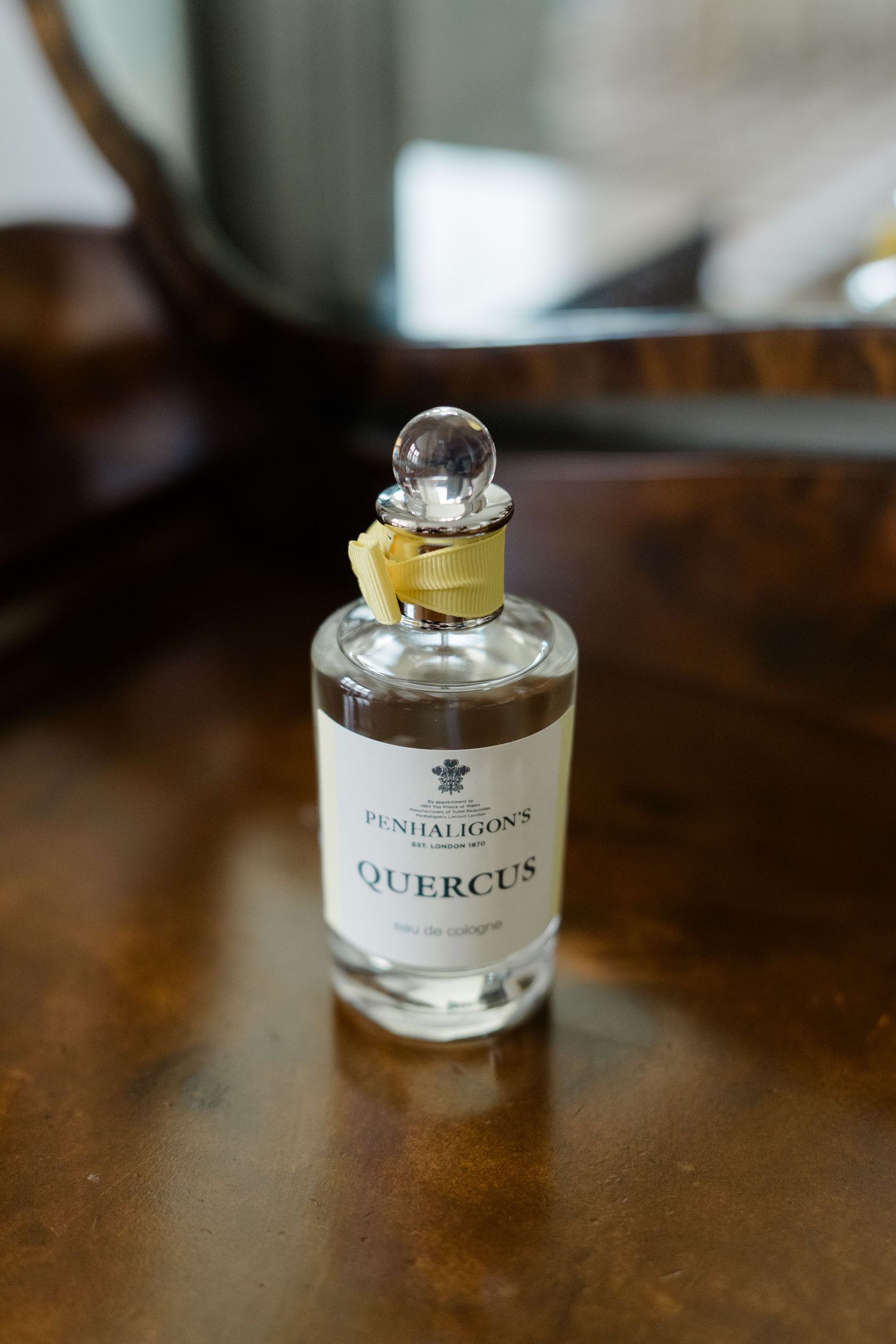 Penhaligons Quercus eau de cologne bottle with yellow ribbon on a wooden surface.