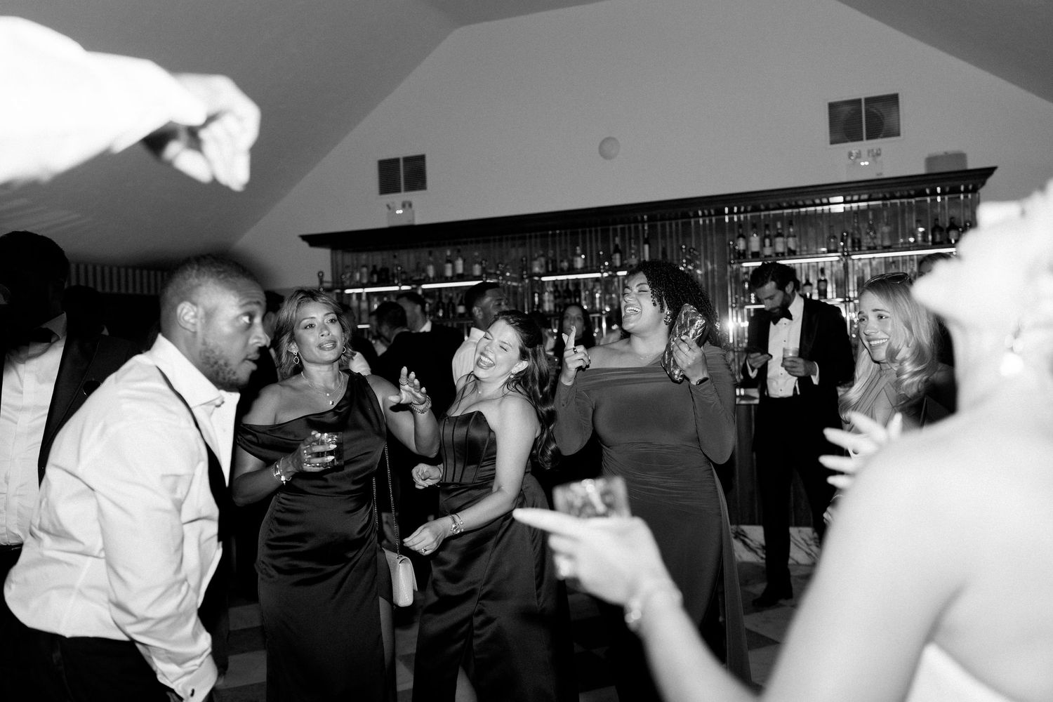 Wedding guests dancing and celebrating on dance floor at evening wedding reception.