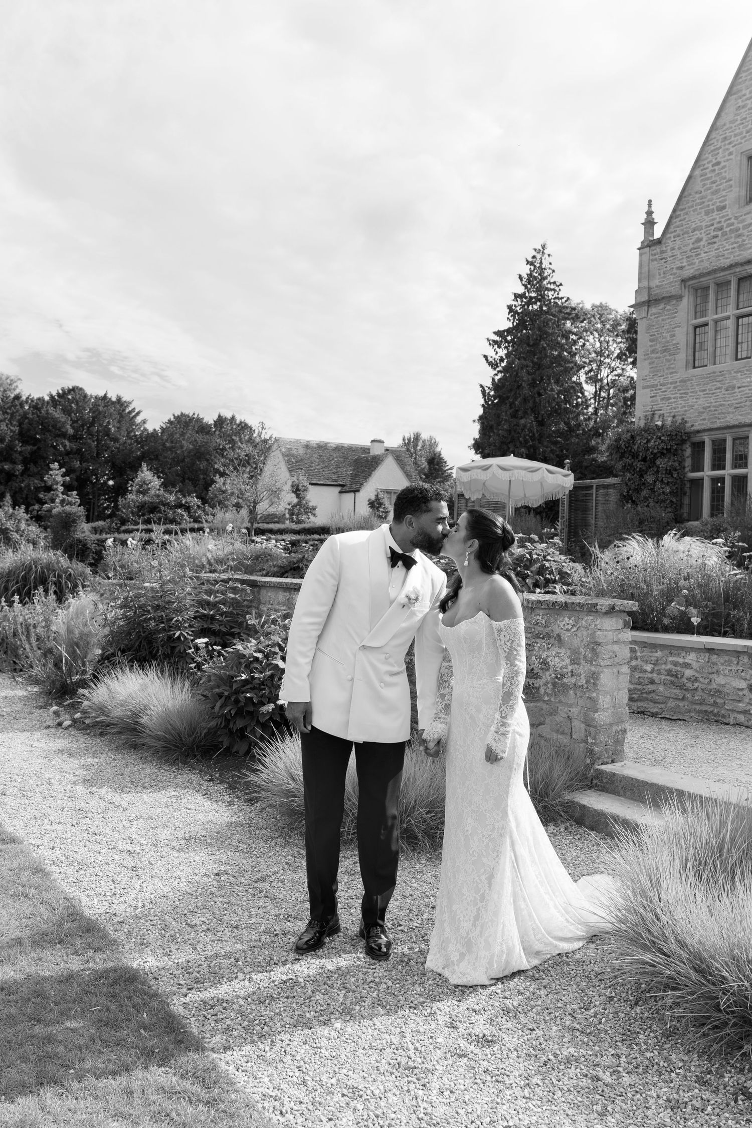 Black and white romantic portrait of bride and groom sharing intimate moment in manicured English garden.