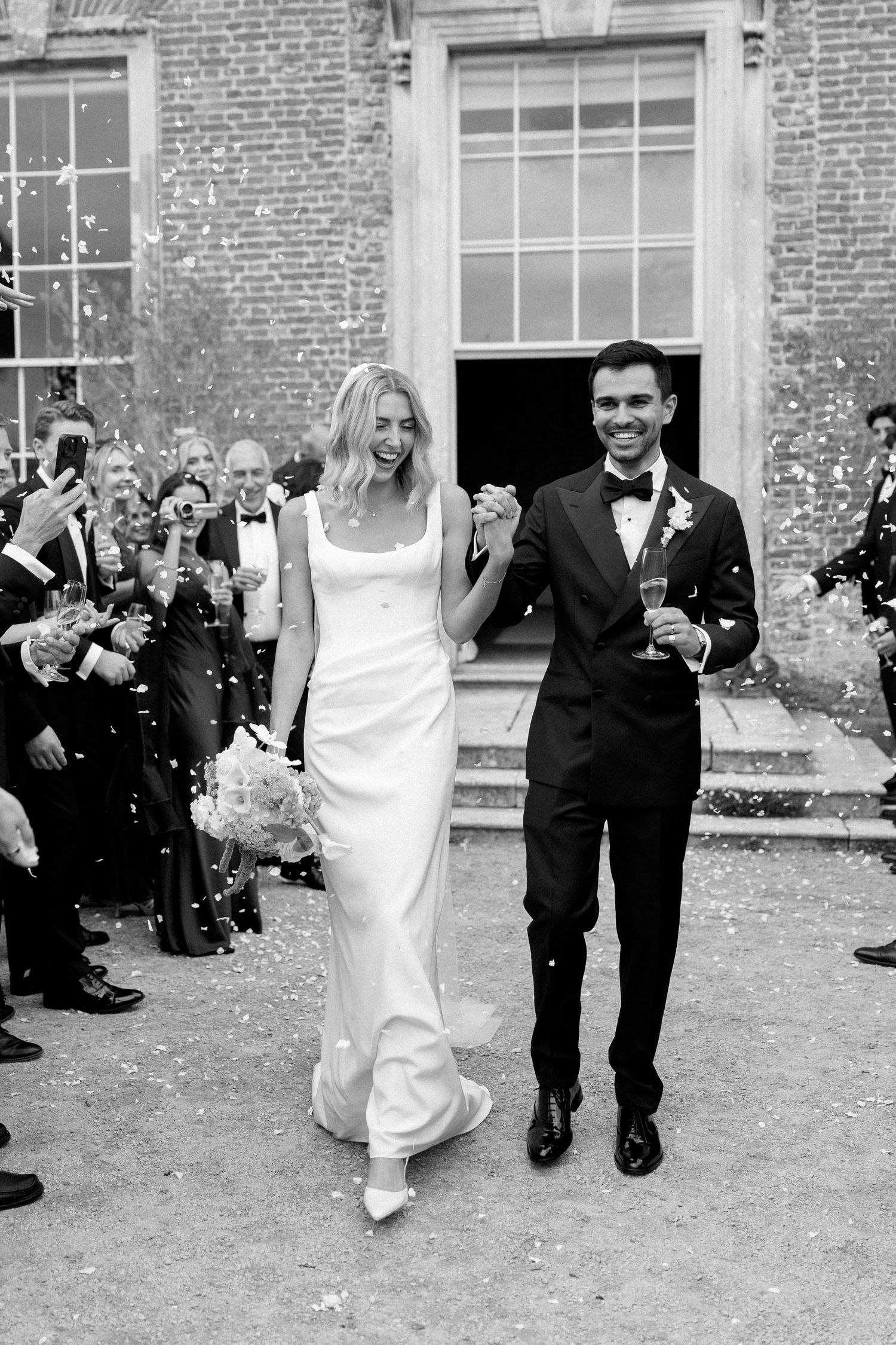 A joyful bride and groom exit a Georgian building through a shower of confetti.