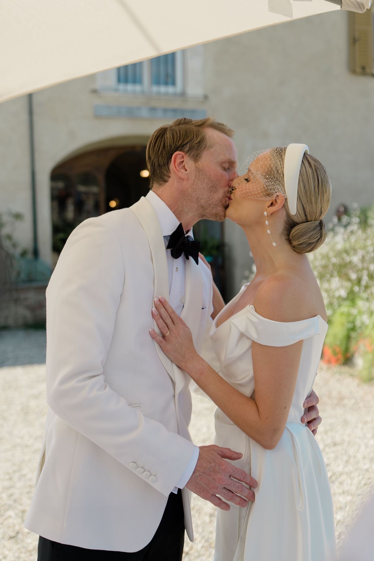 Bride and groom sharing first kiss outdoors at Italian villa wedding ceremony in summer.