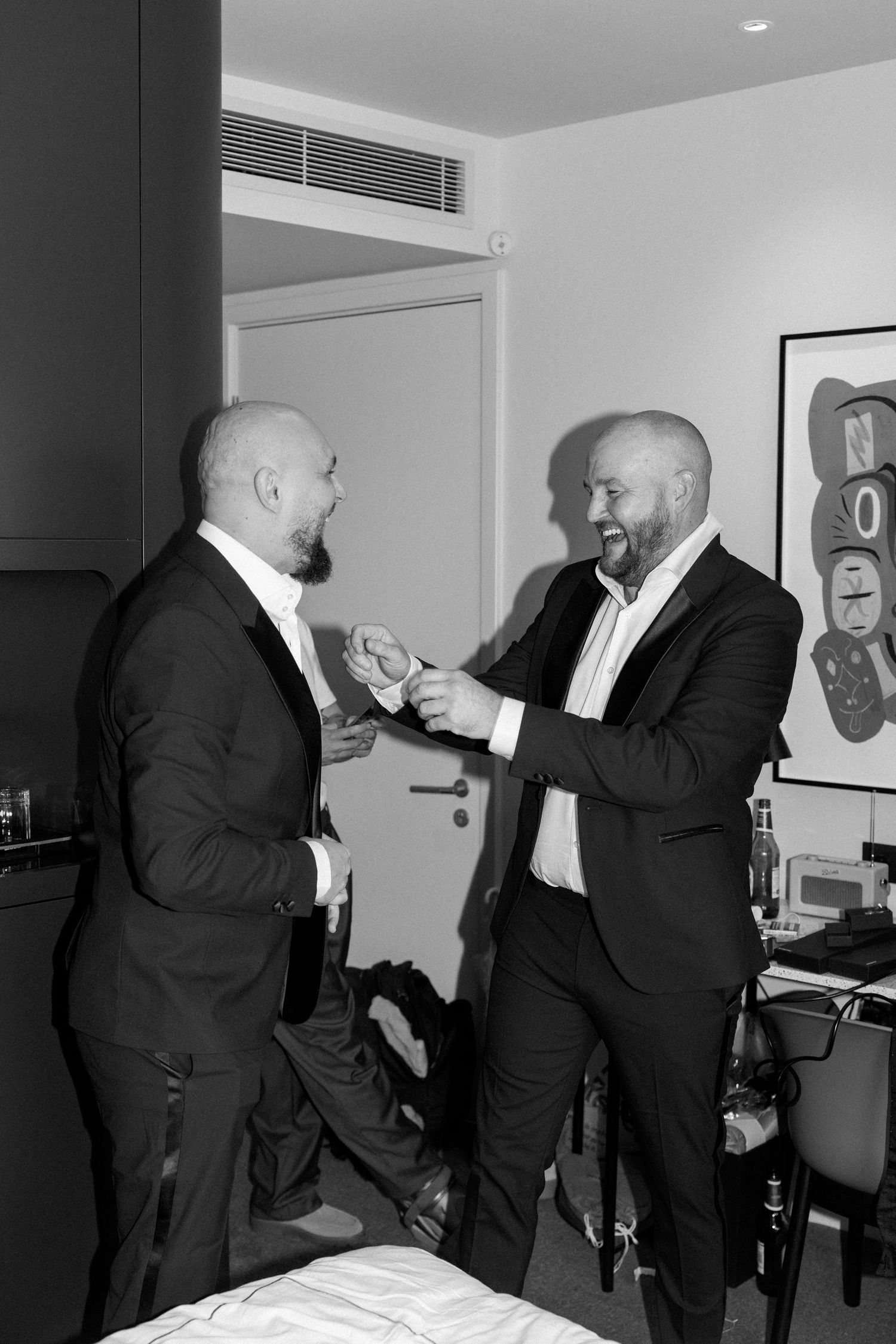 Two men in suits sharing a lighthearted moment in a modern interior setting.