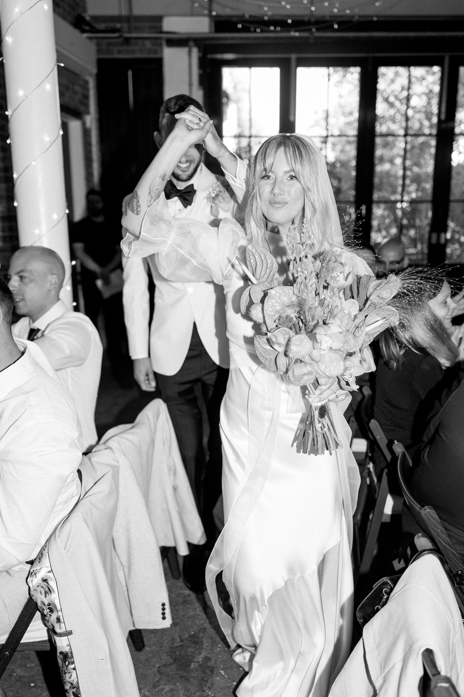 Wedding party members dance and celebrate in black and white formal attire.