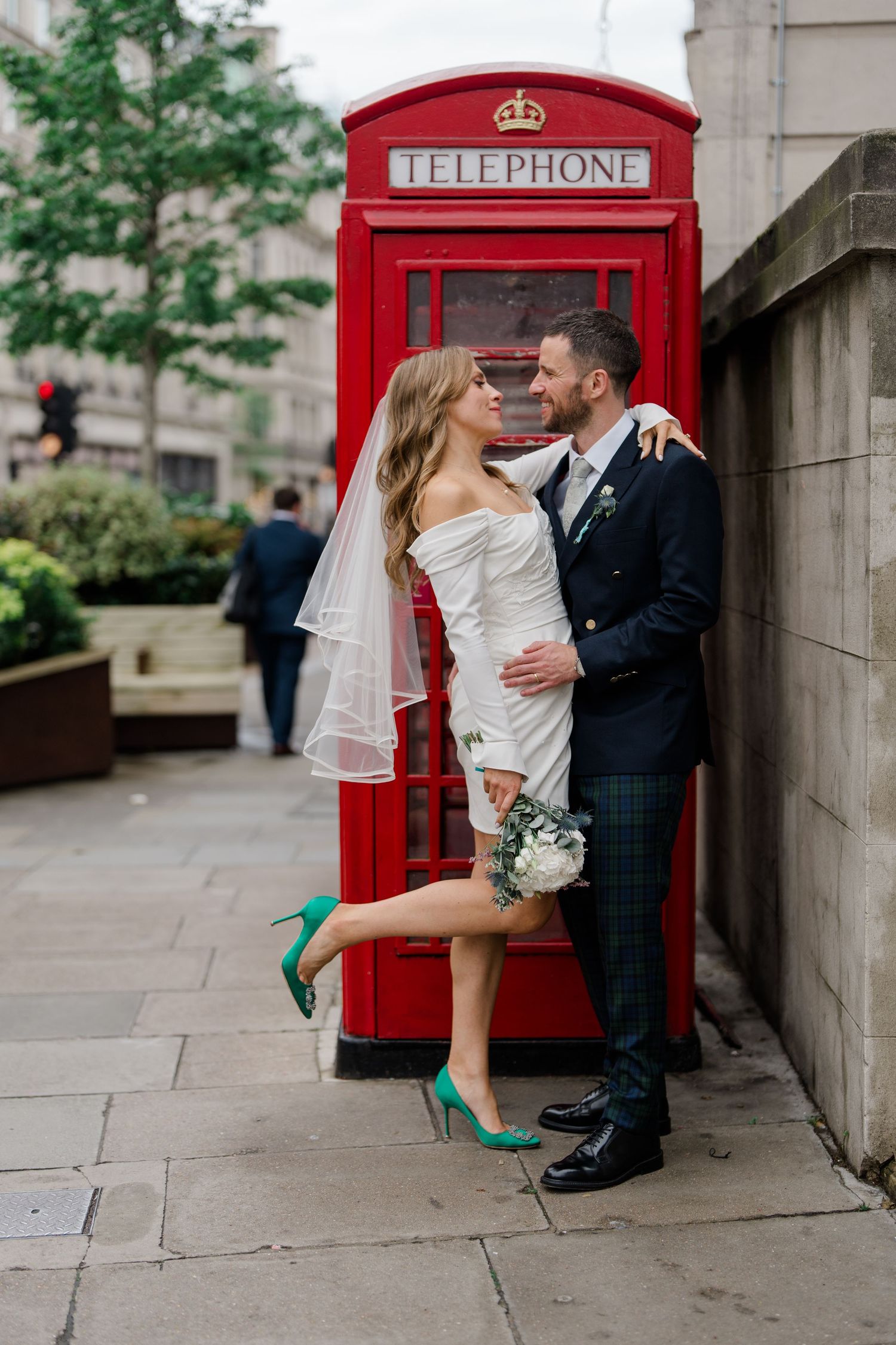 Newlyweds pose playfully by iconic red British telephone boxes.