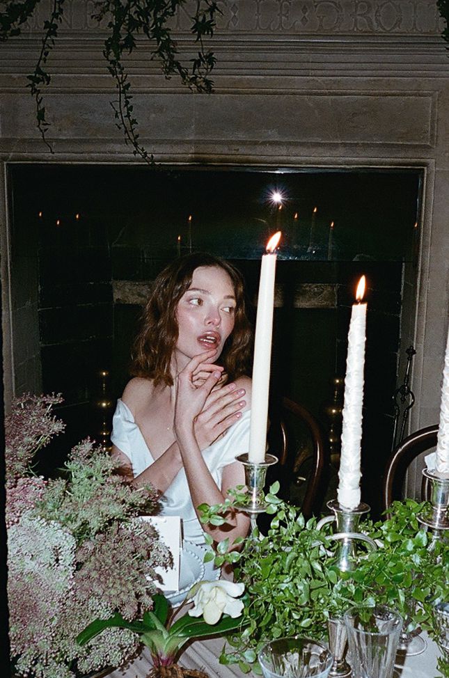 Candlelit table decorated with white flowers and greenery creates romantic dining atmosphere.