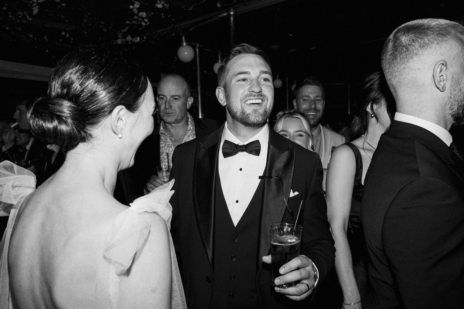 Wedding guests mingling and socializing at evening reception.