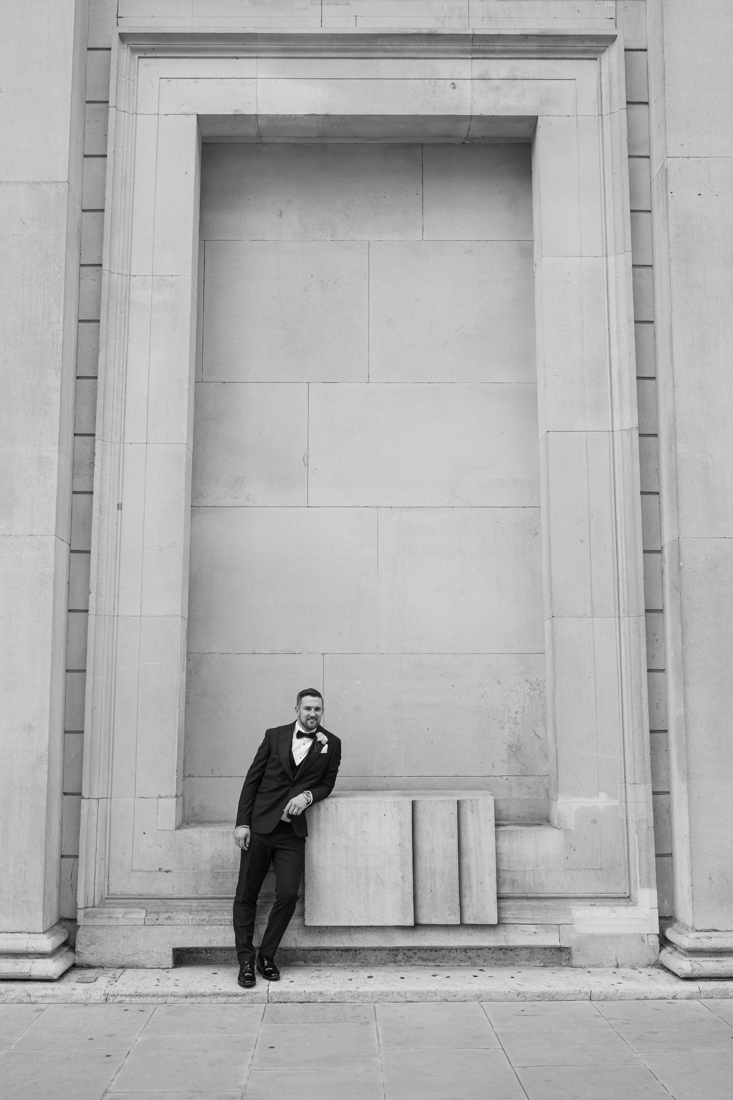 A creative black and white wedding photo series showing a couple playfully hiding behind stone columns.