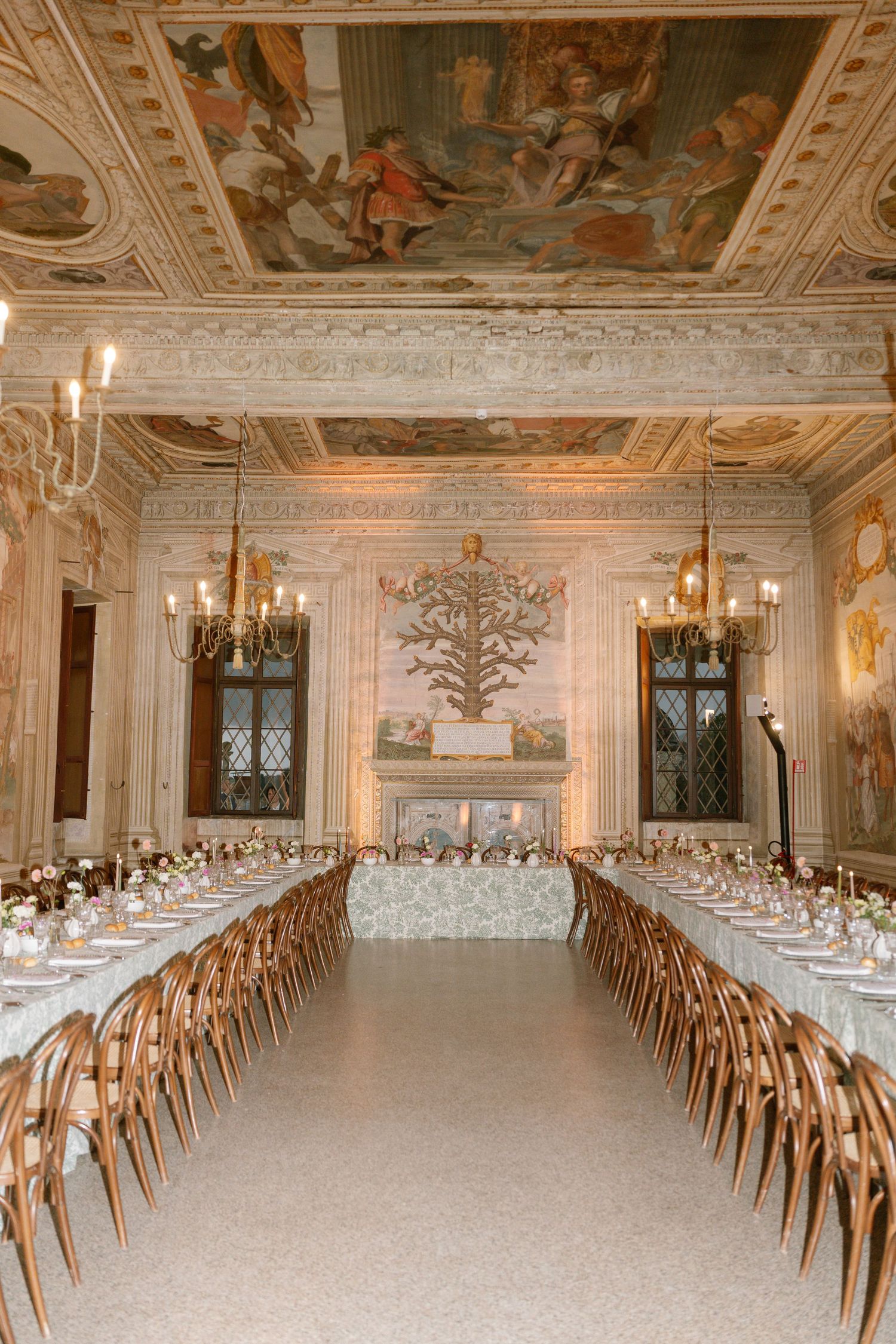 Elegant reception hall with frescoed ceiling and long dining tables set for wedding feast.