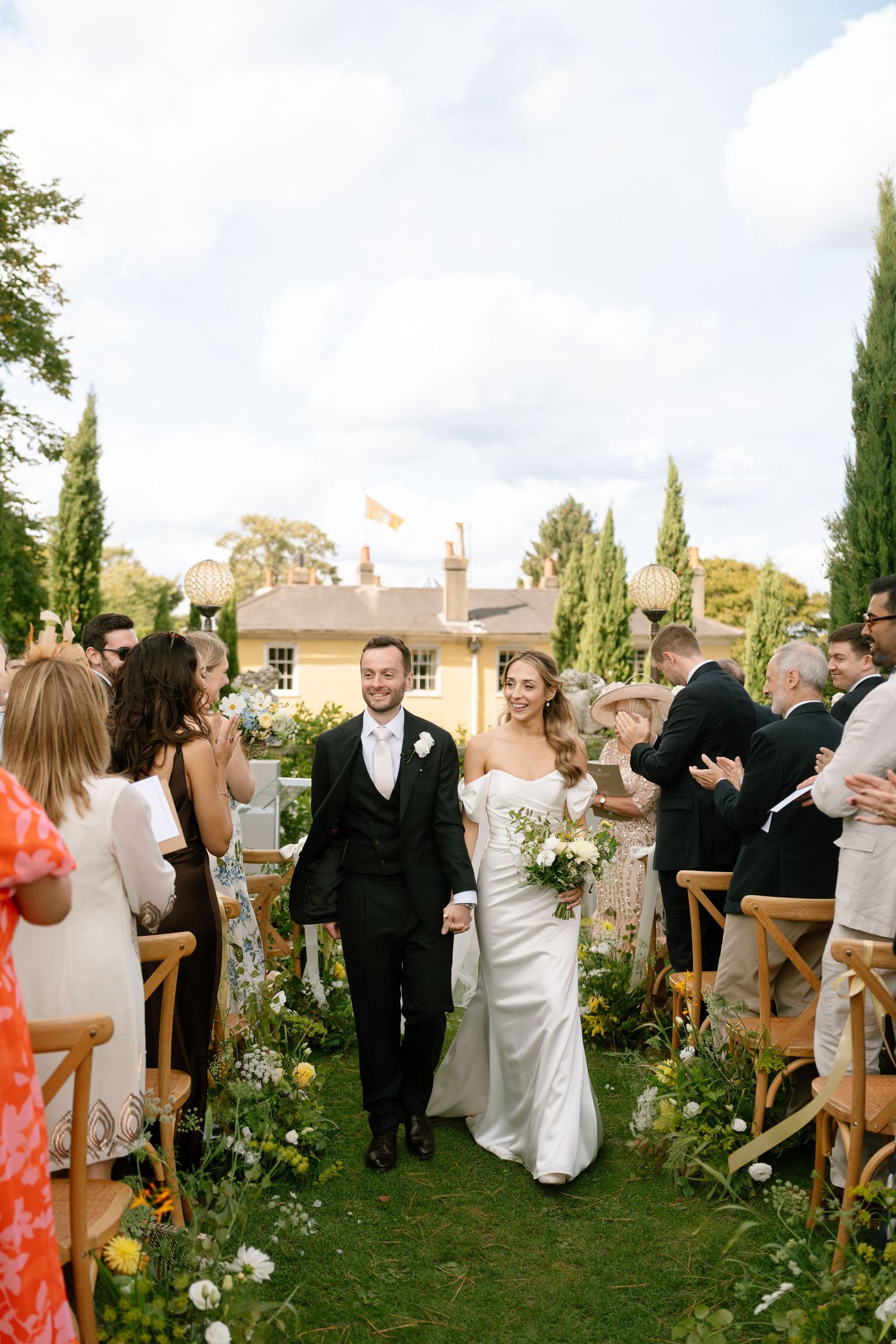 Wedding celebration in garden with guests mingling among floral decorations.