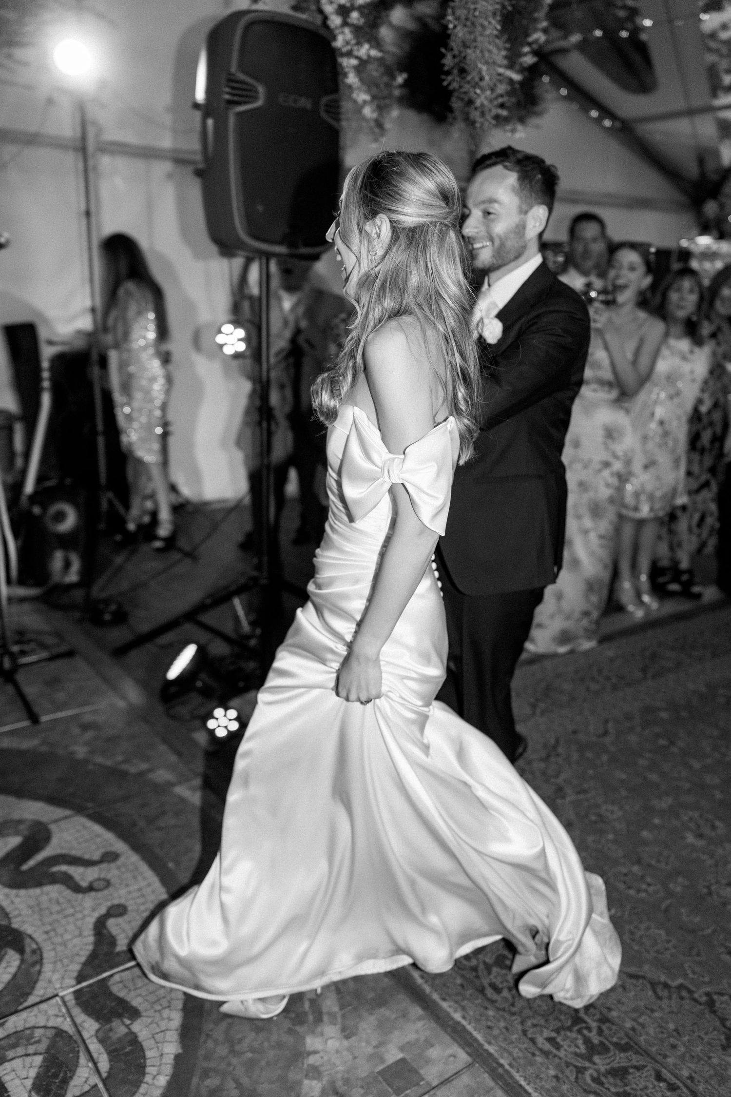 A couple shares an intimate dance moment under hanging greenery at their wedding reception.