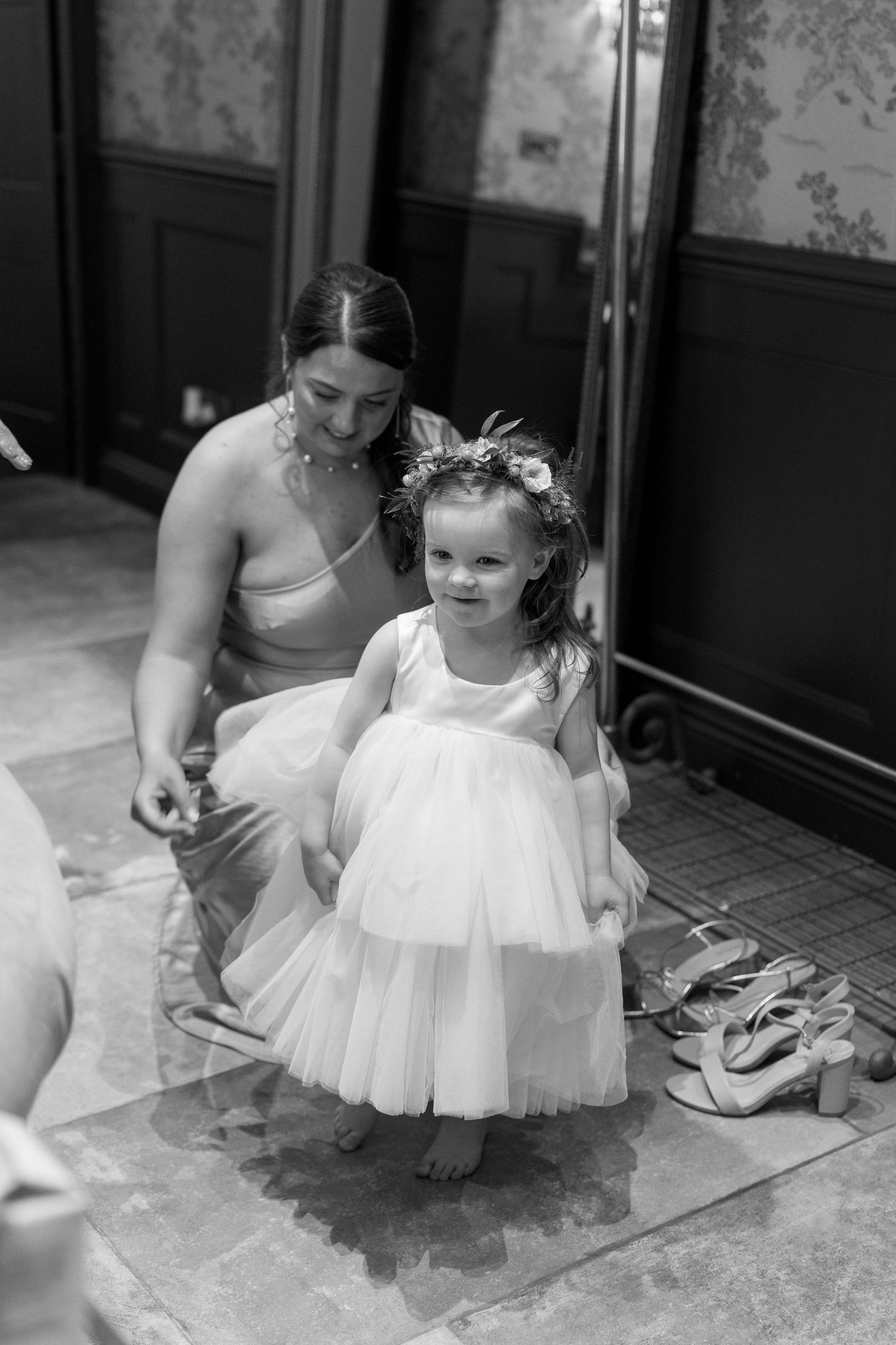 A tender moment of helping a small flower girl adjust her white tulle dress.