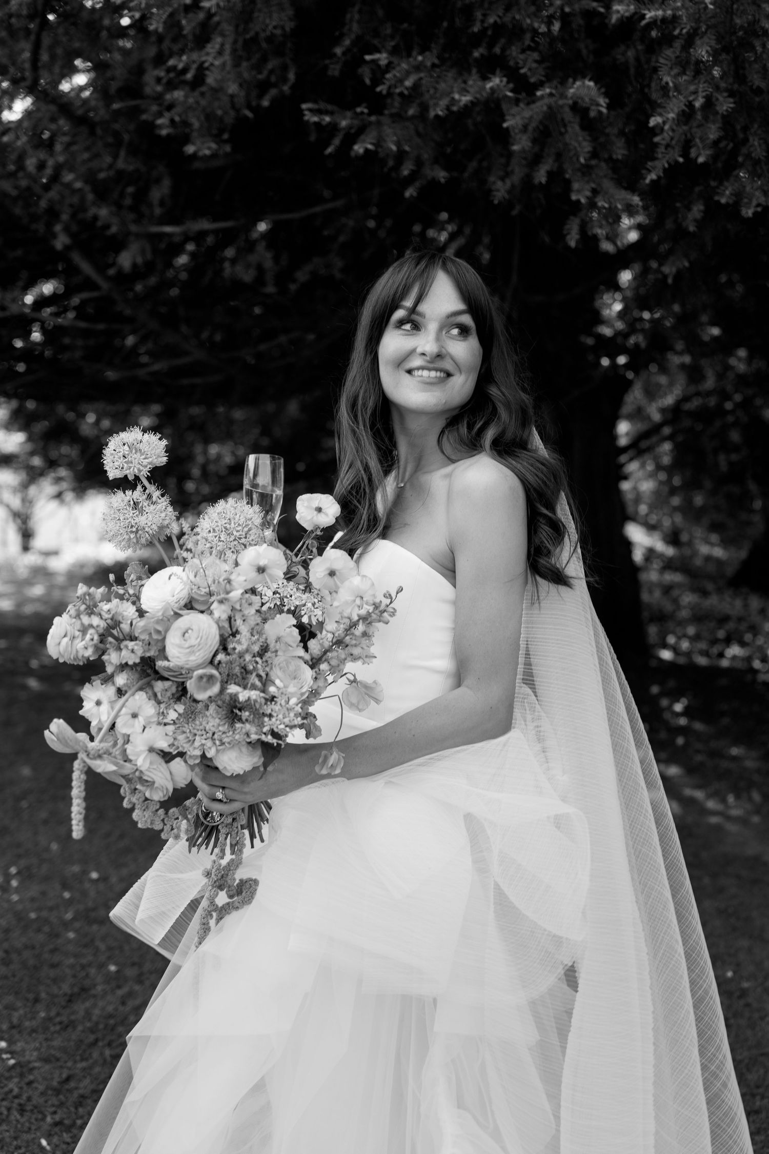 Black and white portrait showcasing flowing wedding dress and floral bouquet.