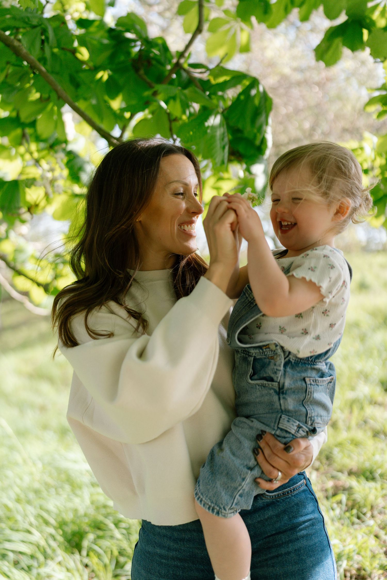 A joyful outdoor moment under green leaves on a sunny day.