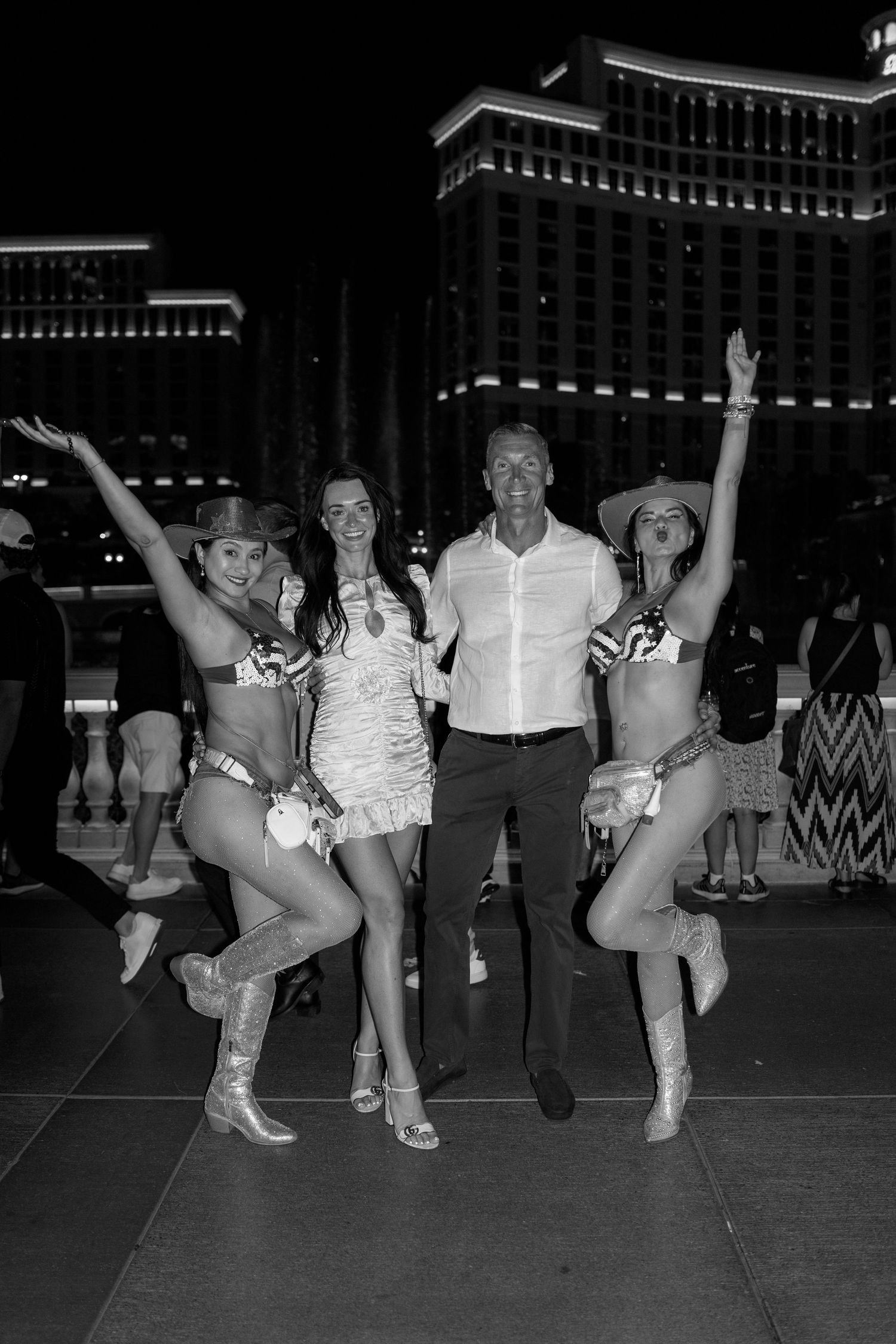 A celebratory group photo with Vegas showgirls in front of the Bellagio at night.