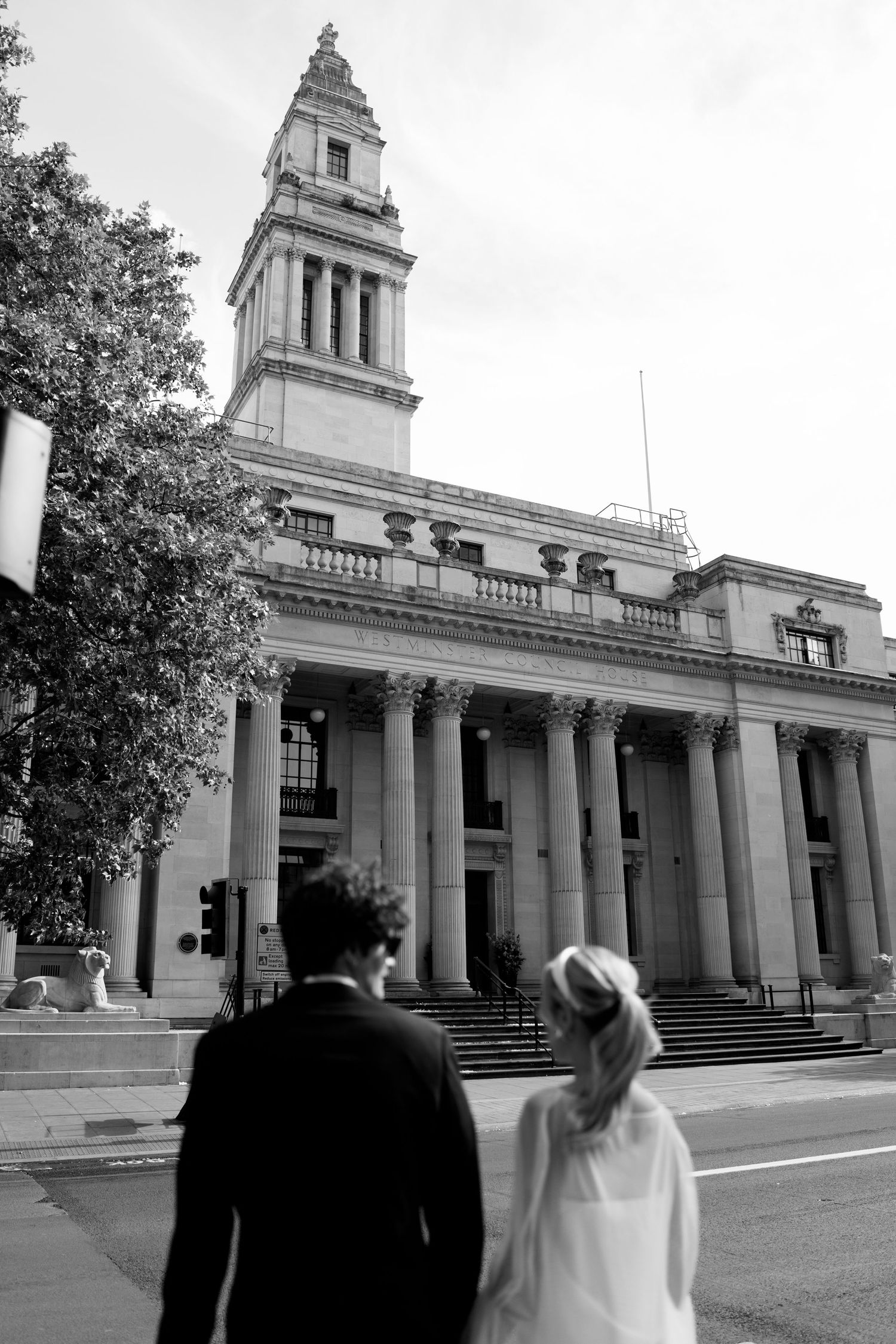 A grand neoclassical building with columns and steps creates an elegant backdrop for a wedding photo shoot.