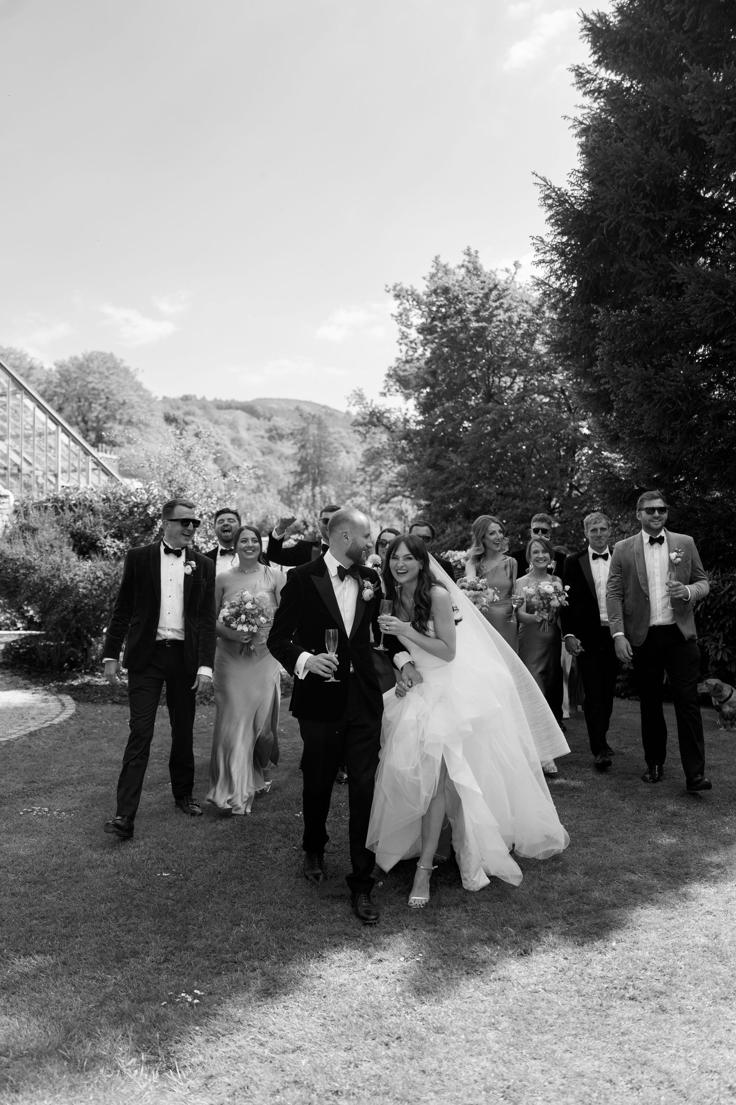 Wedding group walks together on a scenic garden path during celebration.