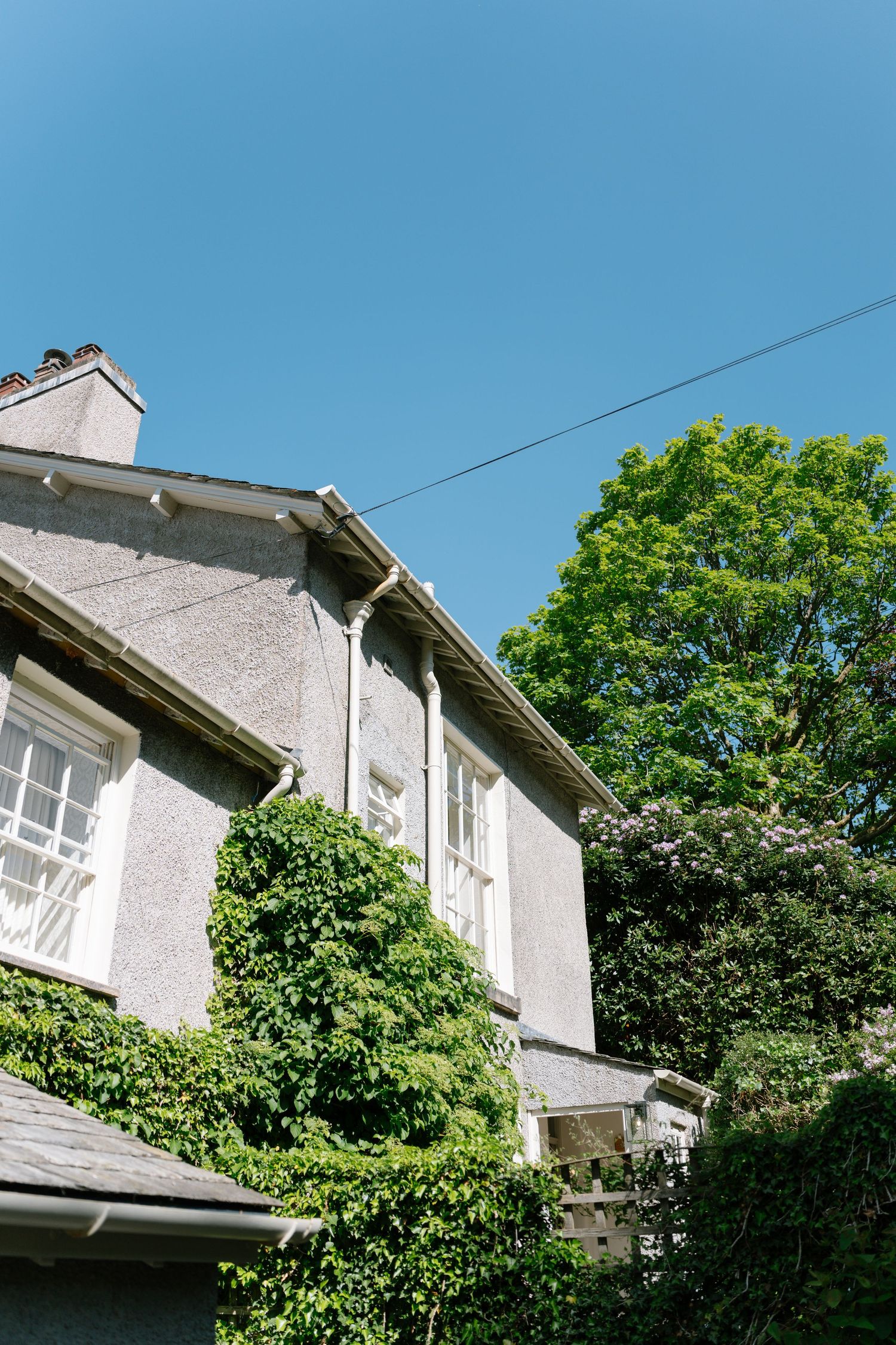 White residential building exterior with green trees against blue sky.