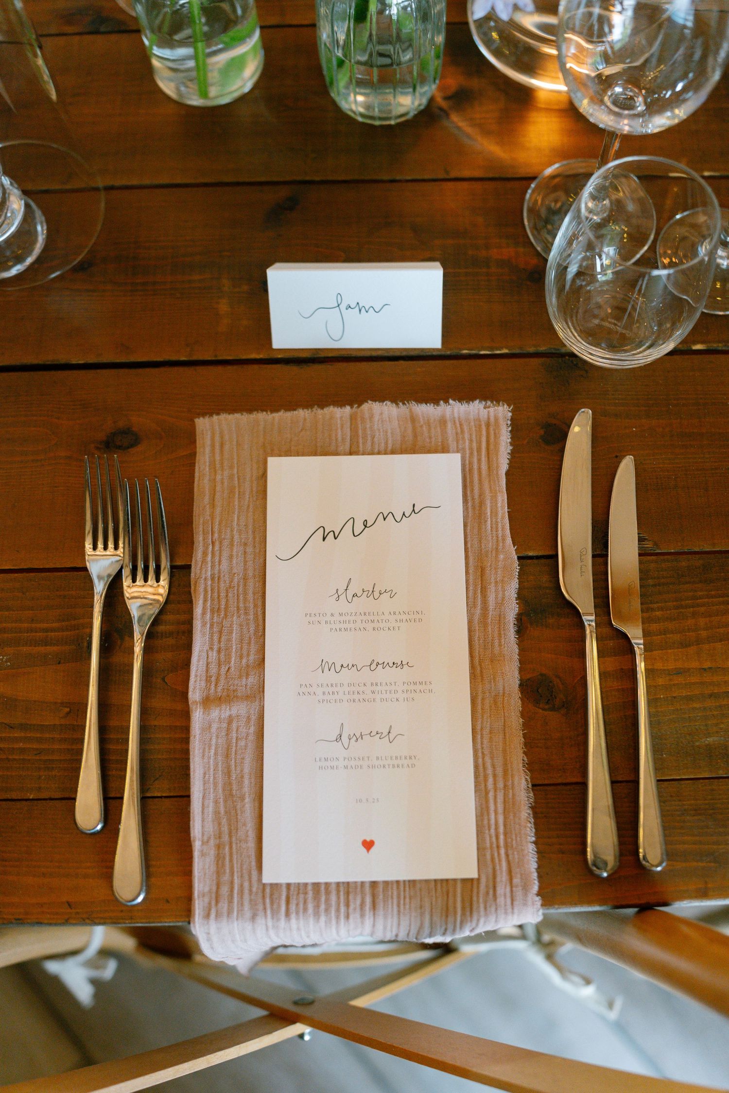 Place settings with menu cards, silverware, and napkins arranged on a wooden dining table.