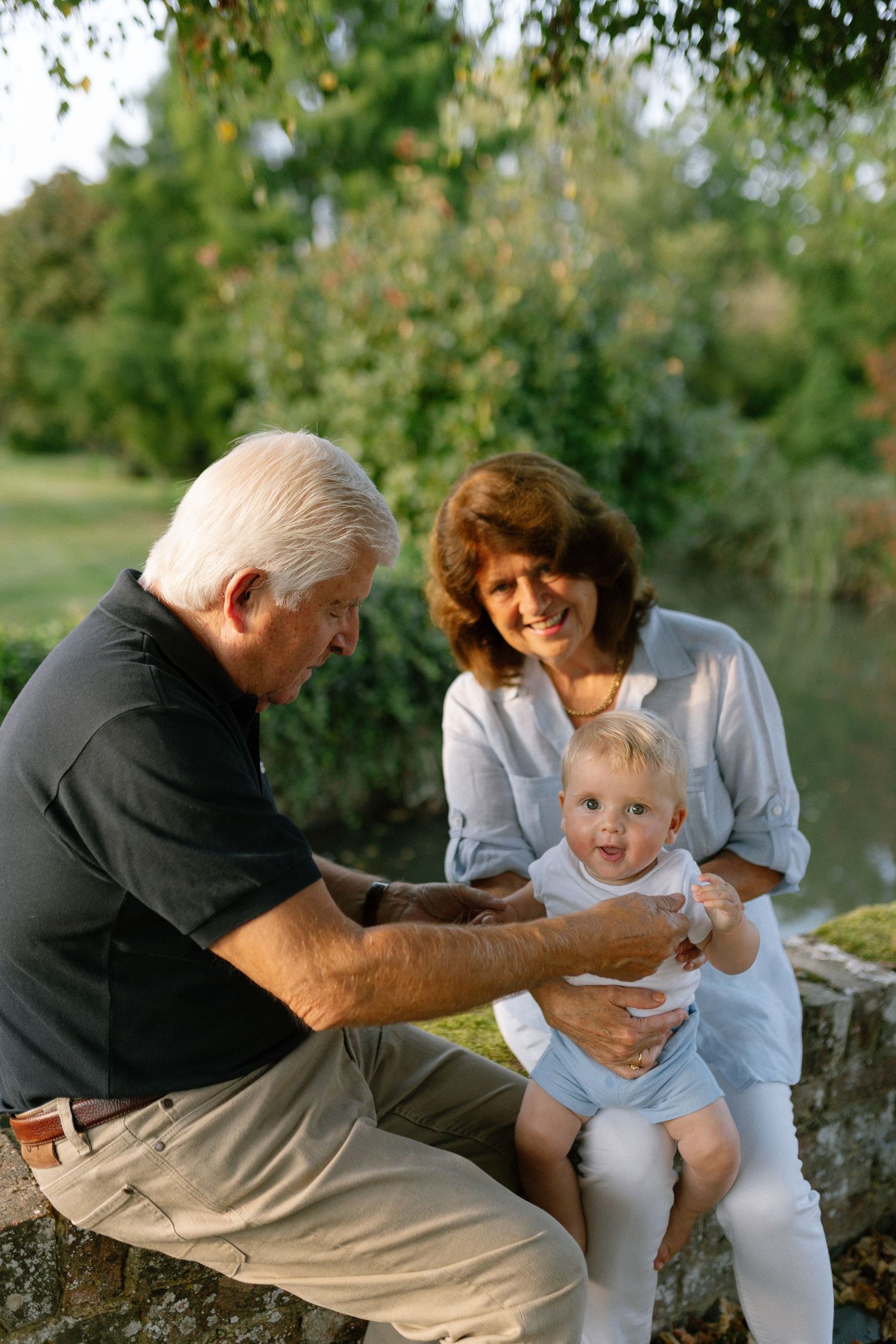 Joyful playtime moments captured on a stone wall by a lake on a sunny afternoon.