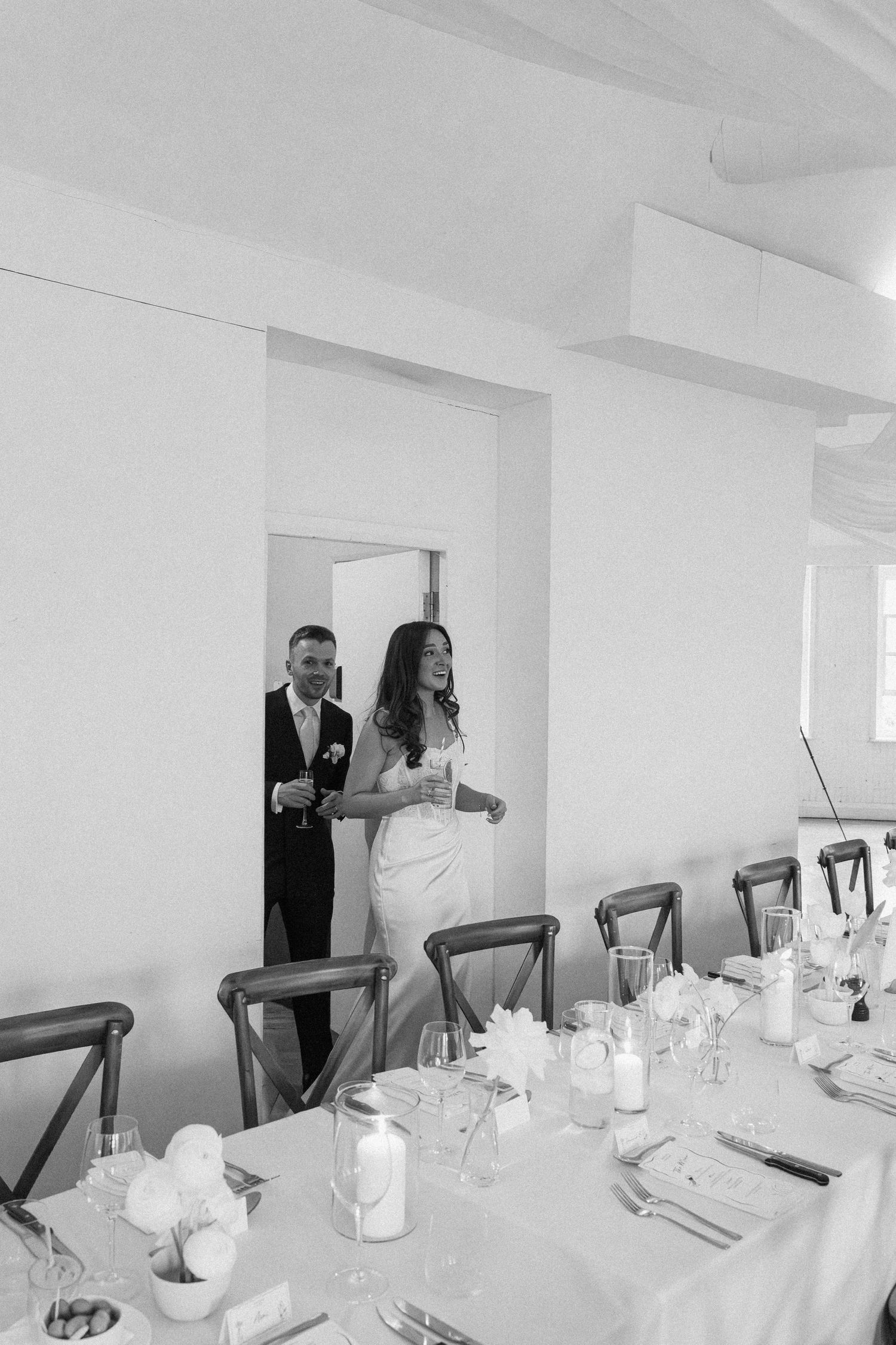 Black and white photo of bride and groom entering their wedding reception hall.