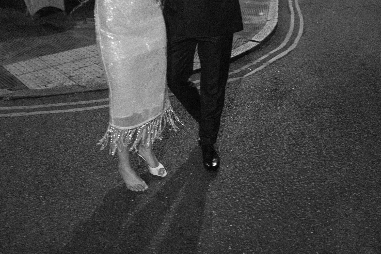 Black and white close-up of a bride and groom walking on a street after their wedding.