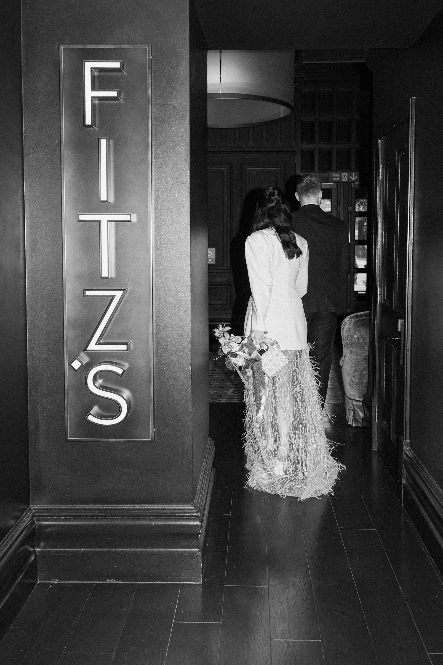 Black and white photo of bride and groom entering Fitz's bar on wedding day.