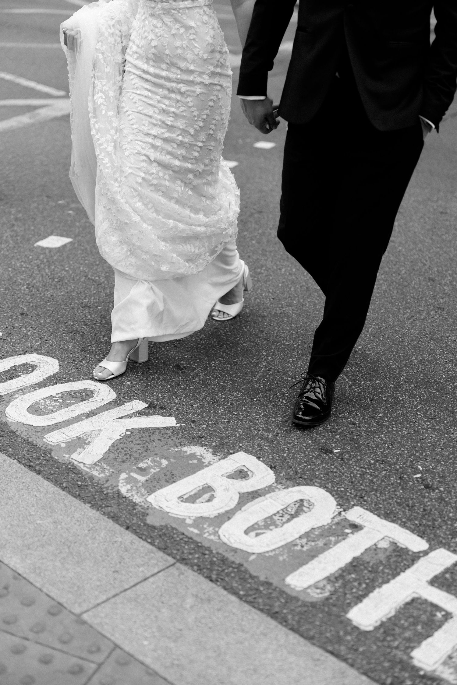 Wedding couple's feet walking across street markings in black and white.