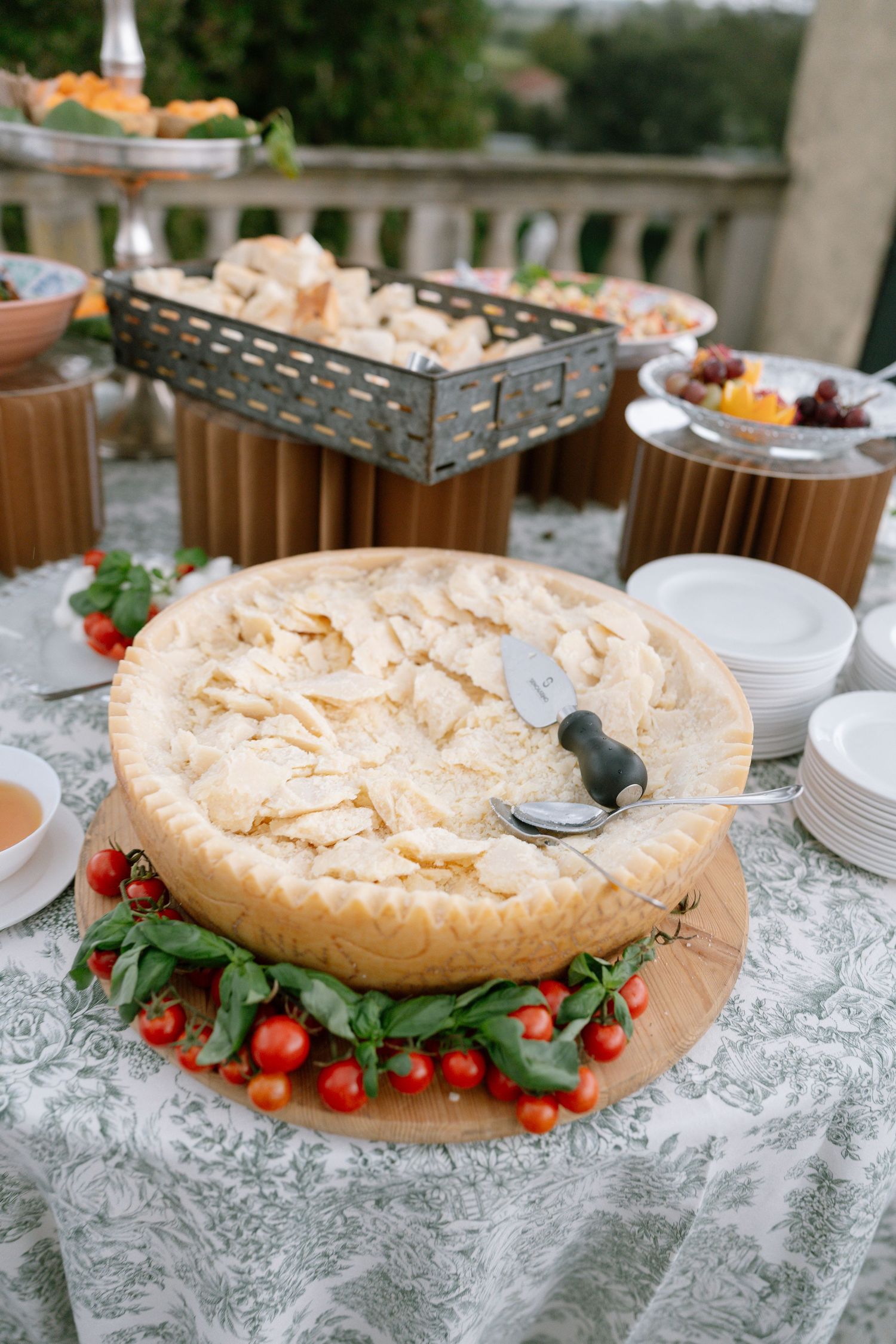Large meringue dessert decorated with fresh cherries and herbs on a lace tablecloth.