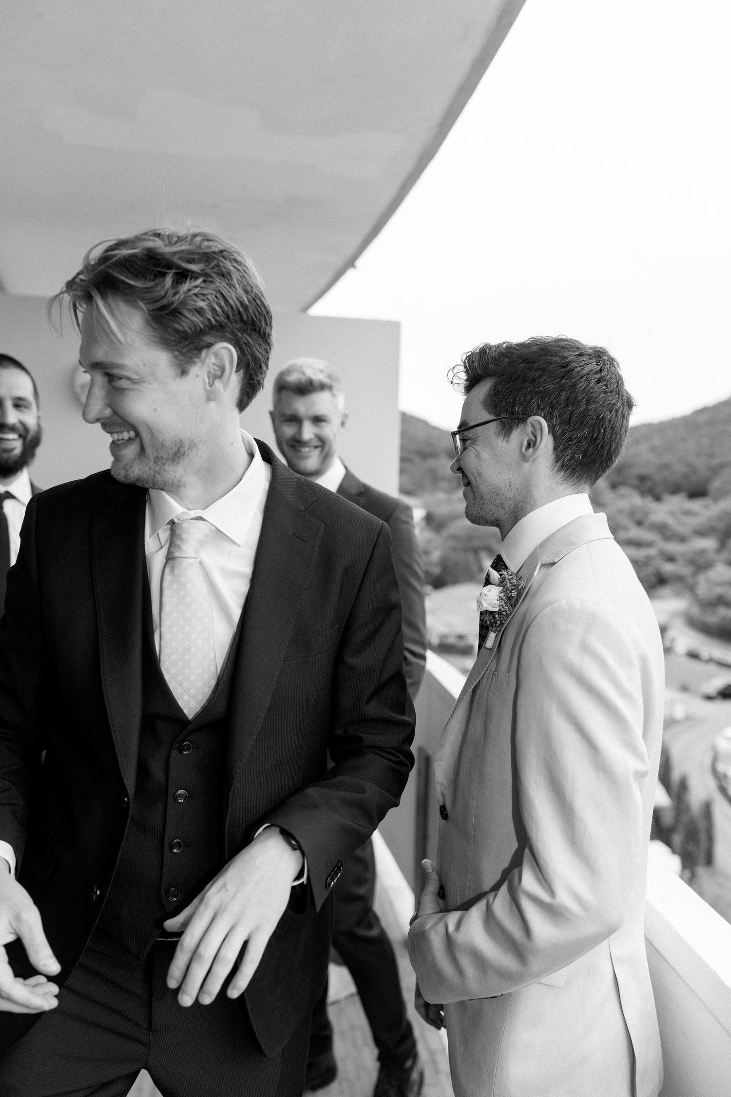 Wedding party members share laughter and smiles during an outdoor gathering.