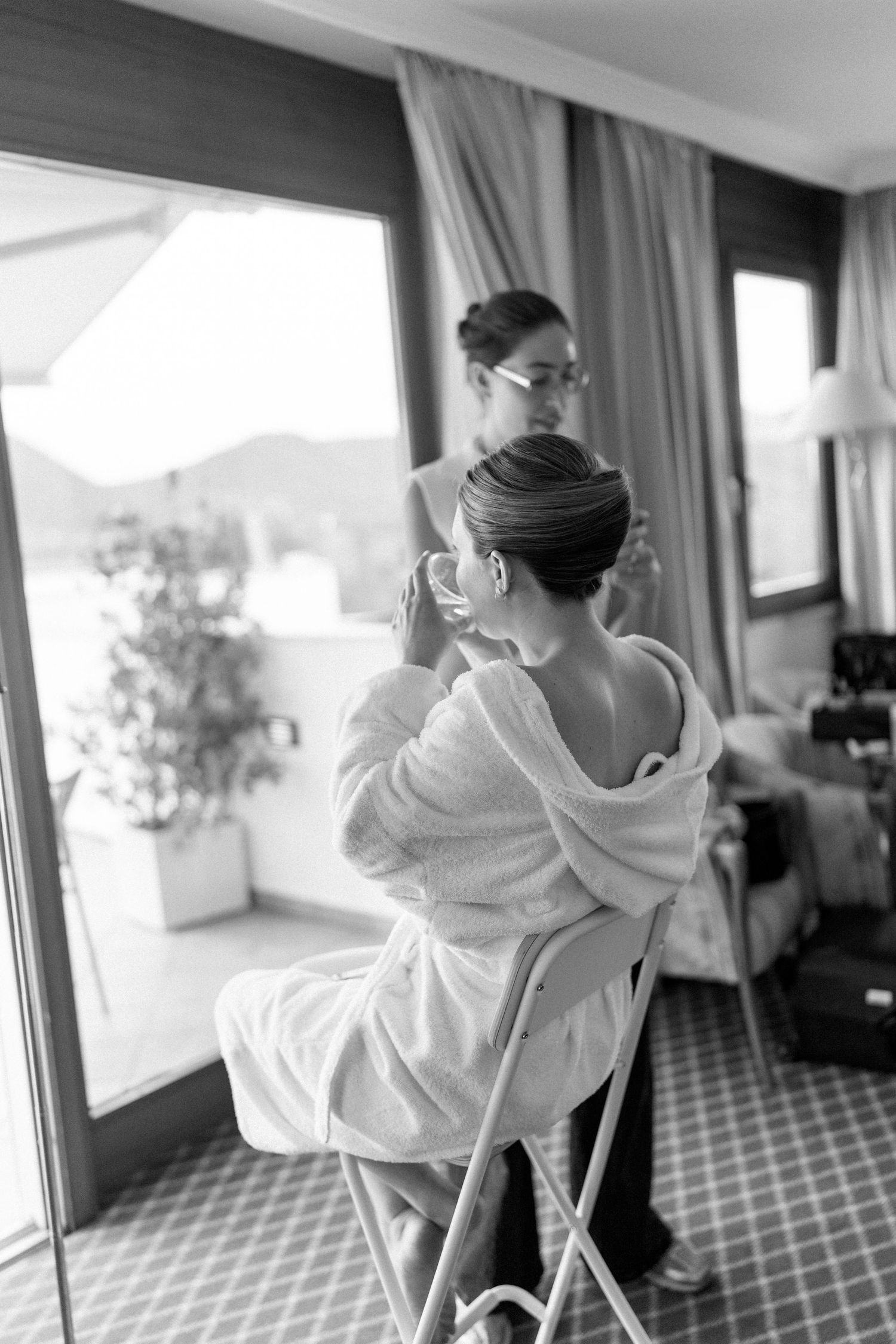 Person in white robe sitting in hotel room with geometric carpet pattern.