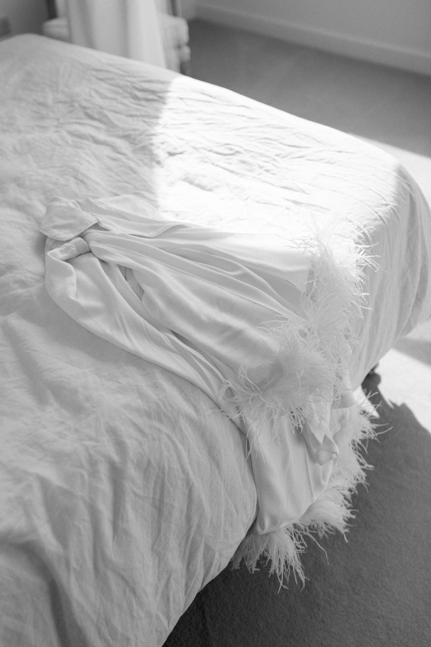 White fabric with feather details draped across a surface in natural light.