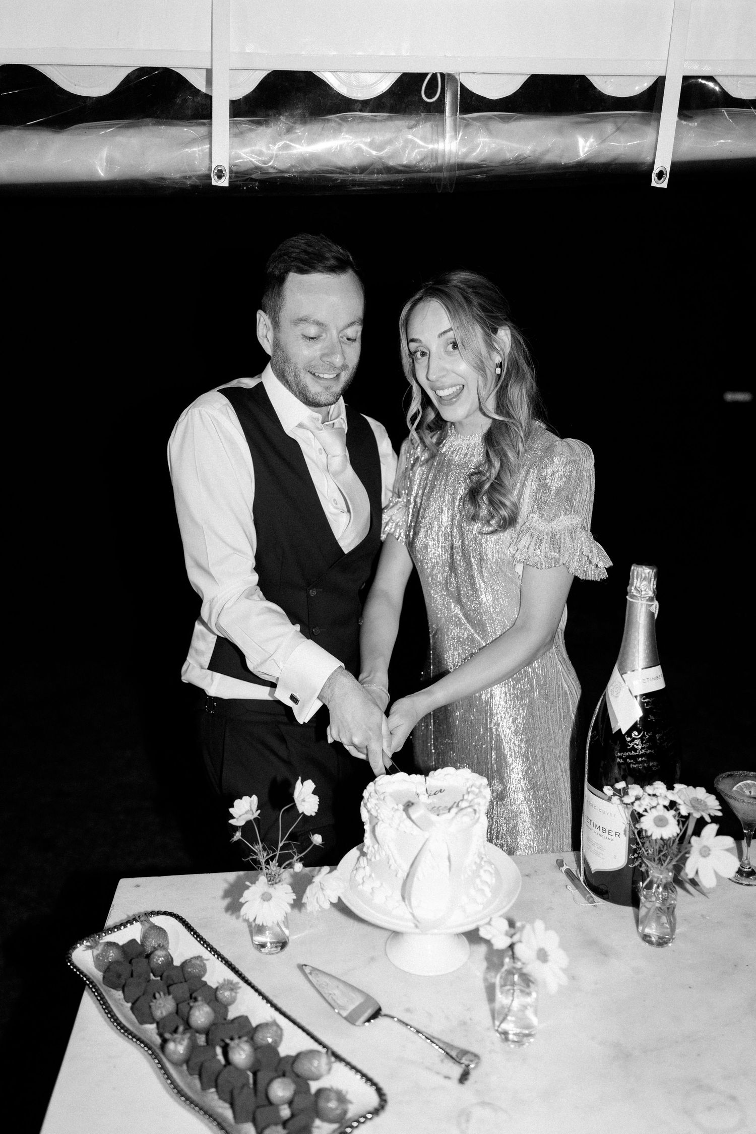 Couple cutting their wedding cake together at a reception table.