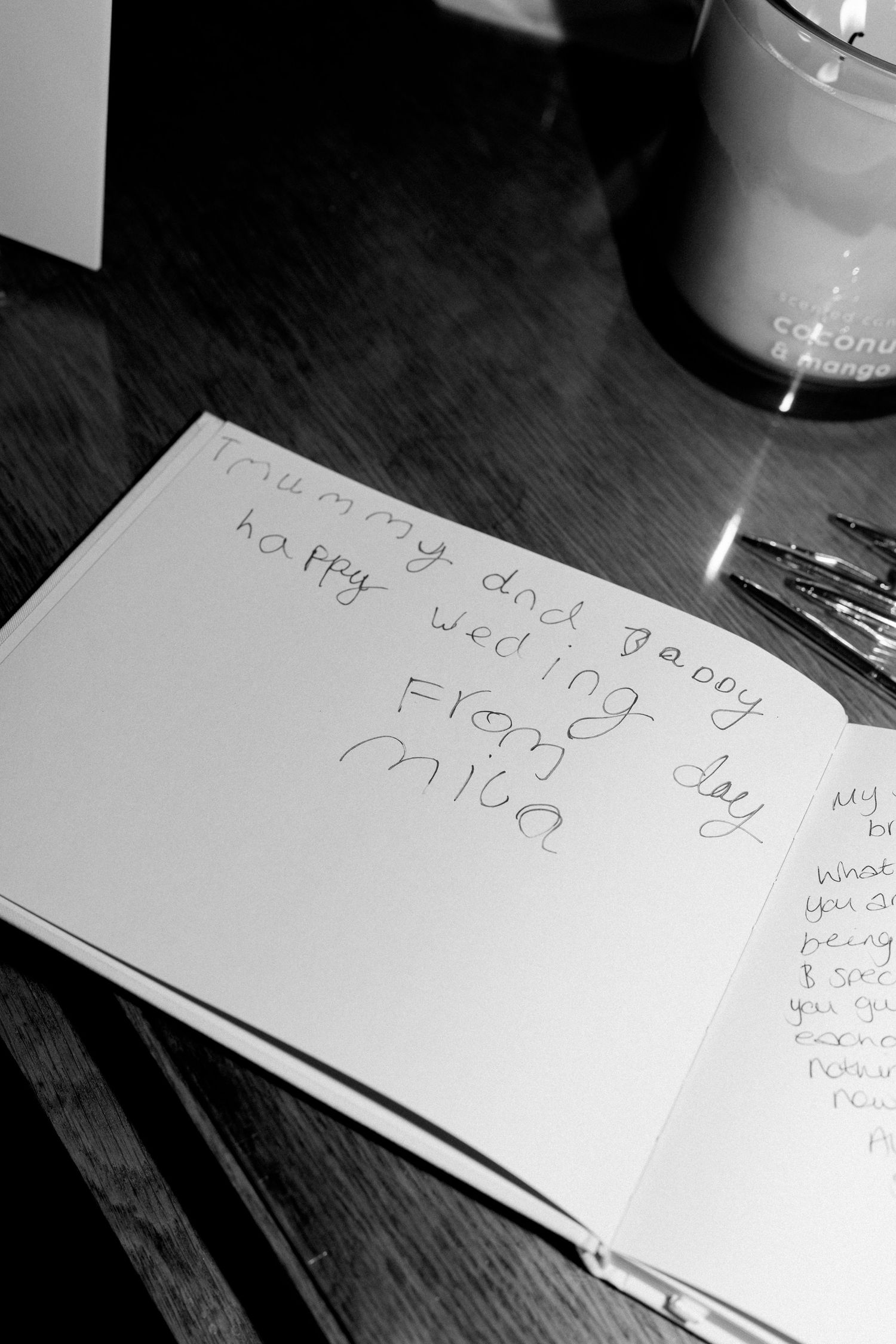 Black and white close-up of a child's heartfelt wedding guest book message reading happy wedding day from Mila.