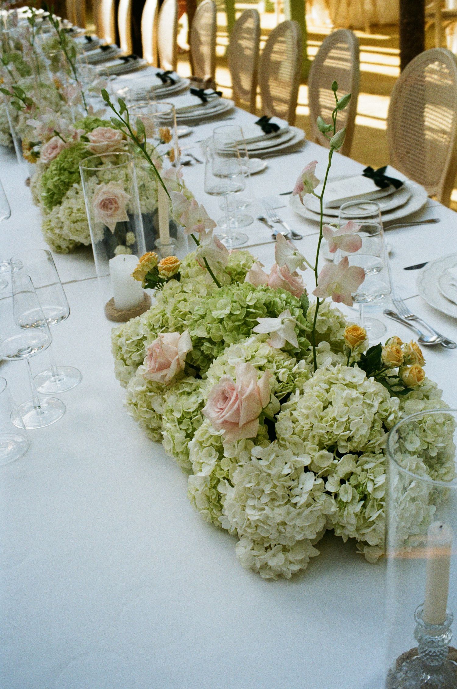 White hydrangeas and pink roses create an elegant centerpiece along a formal dining table.
