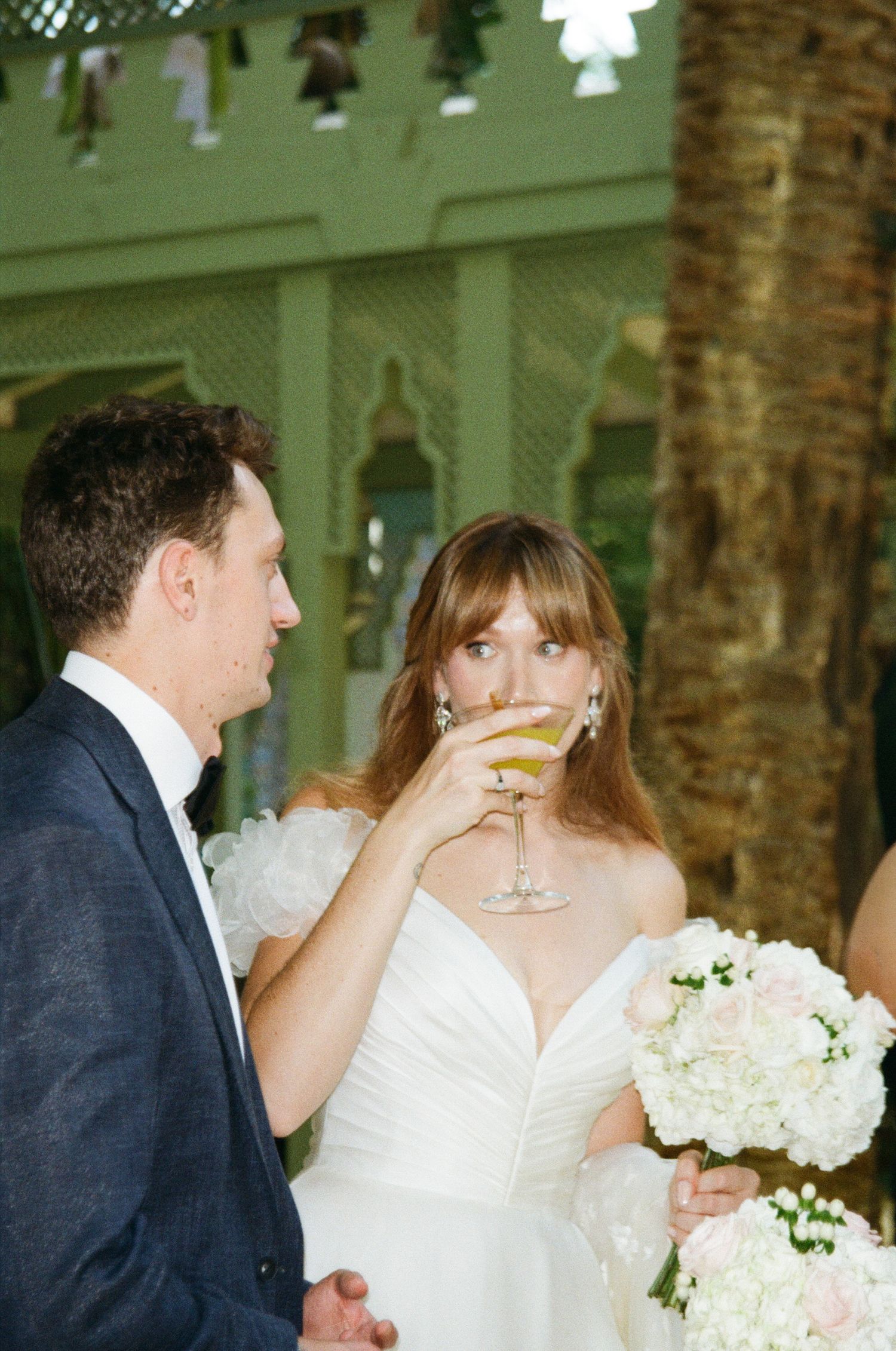 A couple shares a celebratory champagne toast at their elegant wedding reception with white floral decor.