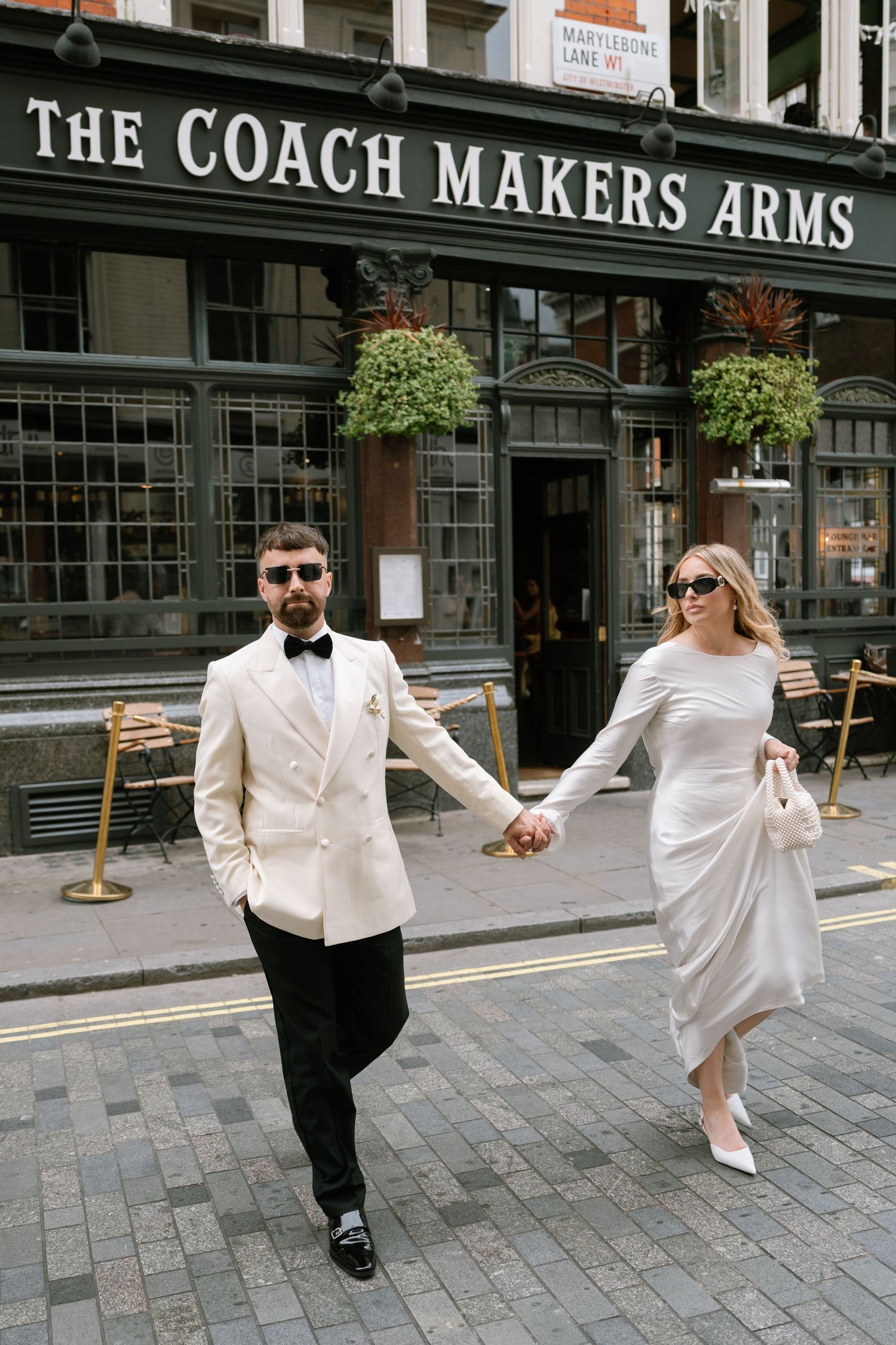 Playful wedding photos outside The Coach Makers Arms pub.