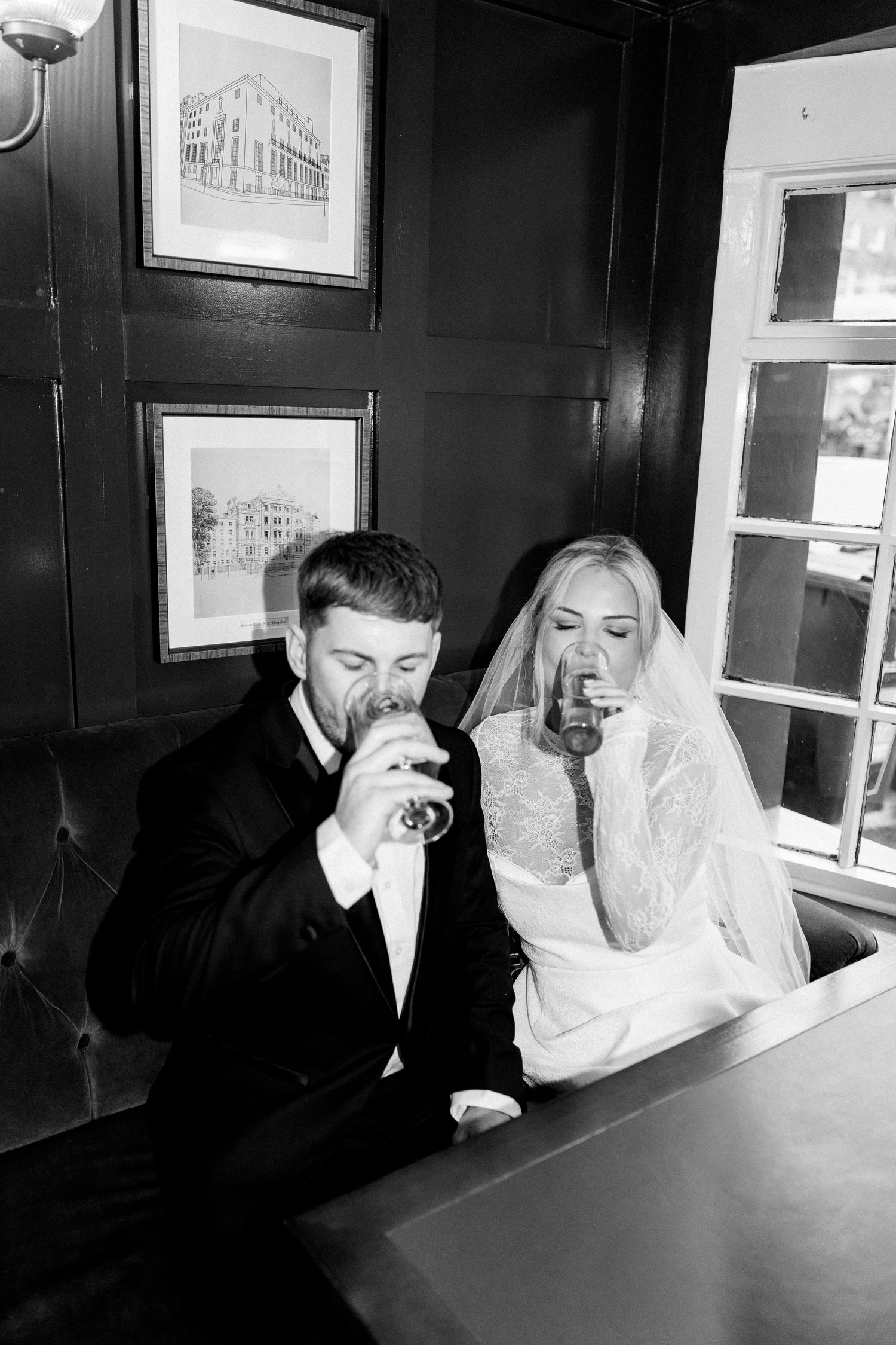 Black and white photos of a couple sharing laughter at a table with framed artwork on the wall.