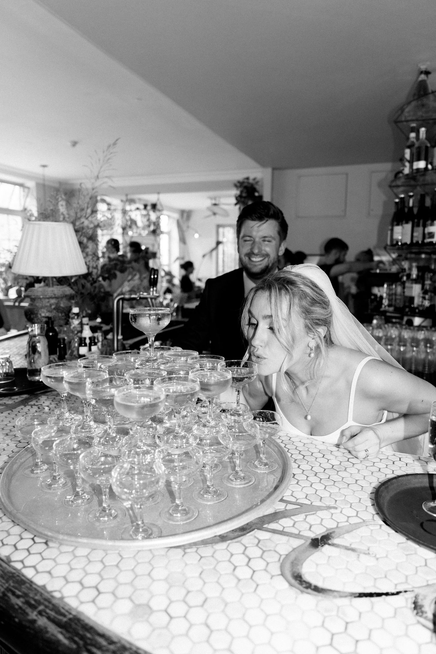 Celebration at a bar with champagne glasses arranged on a tiled counter.