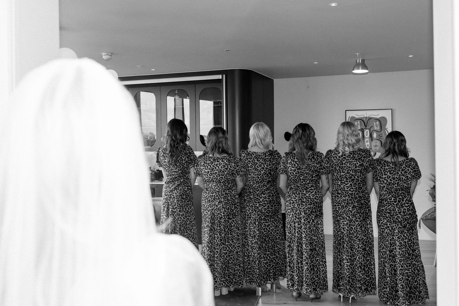Black and white photo of bridesmaids in matching polka dot dresses viewed from behind.