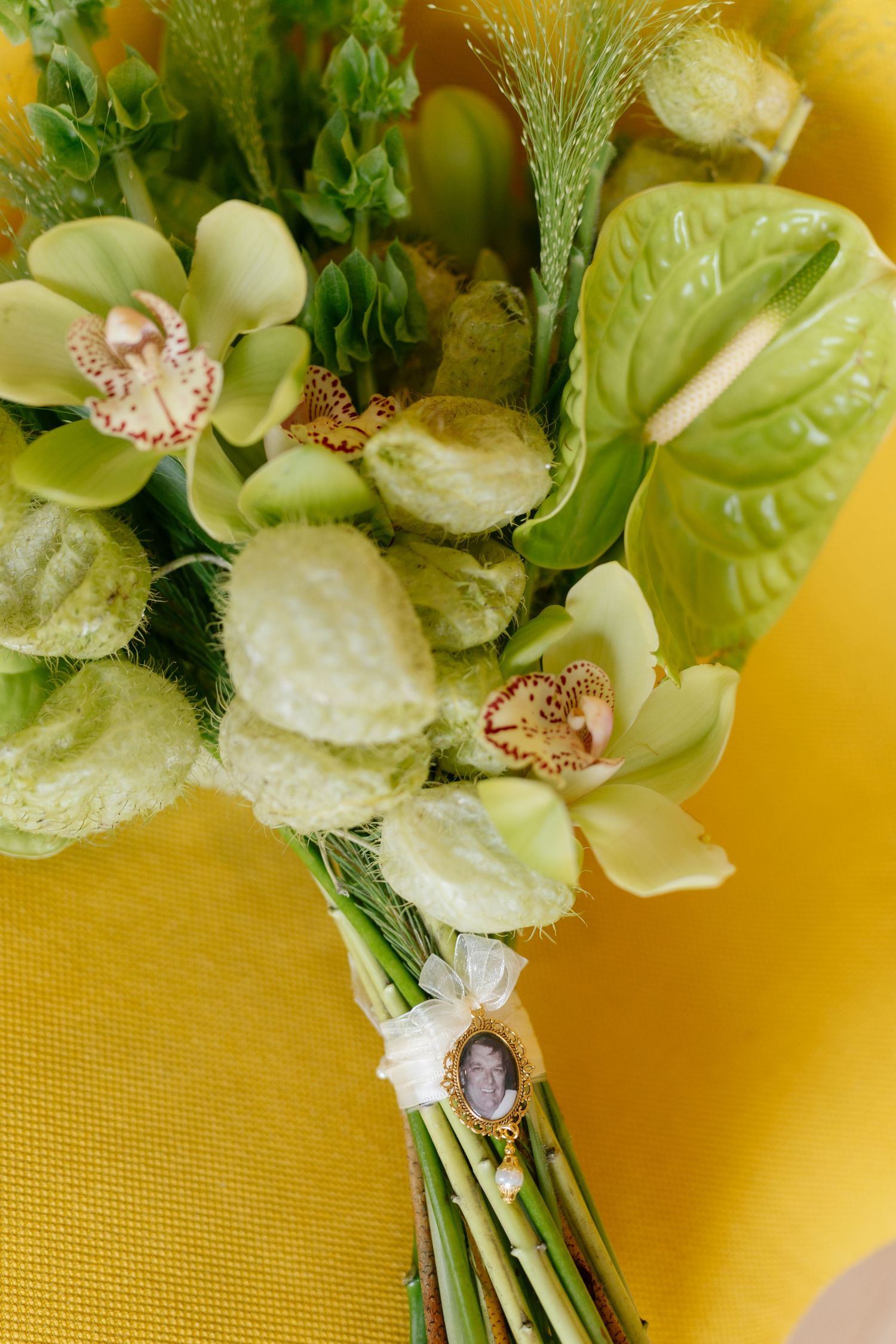 Close-up of a delicate green and white floral bouquet arrangement against a warm yellow background.