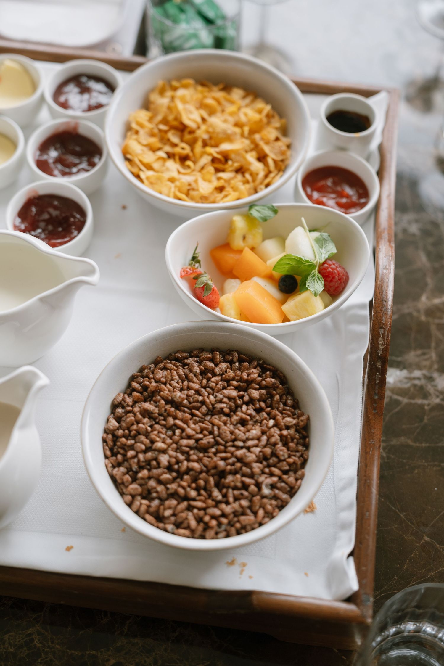 White ceramic divided serving dish containing chocolate chips, fresh fruit, and breakfast cereal arranged in sections.