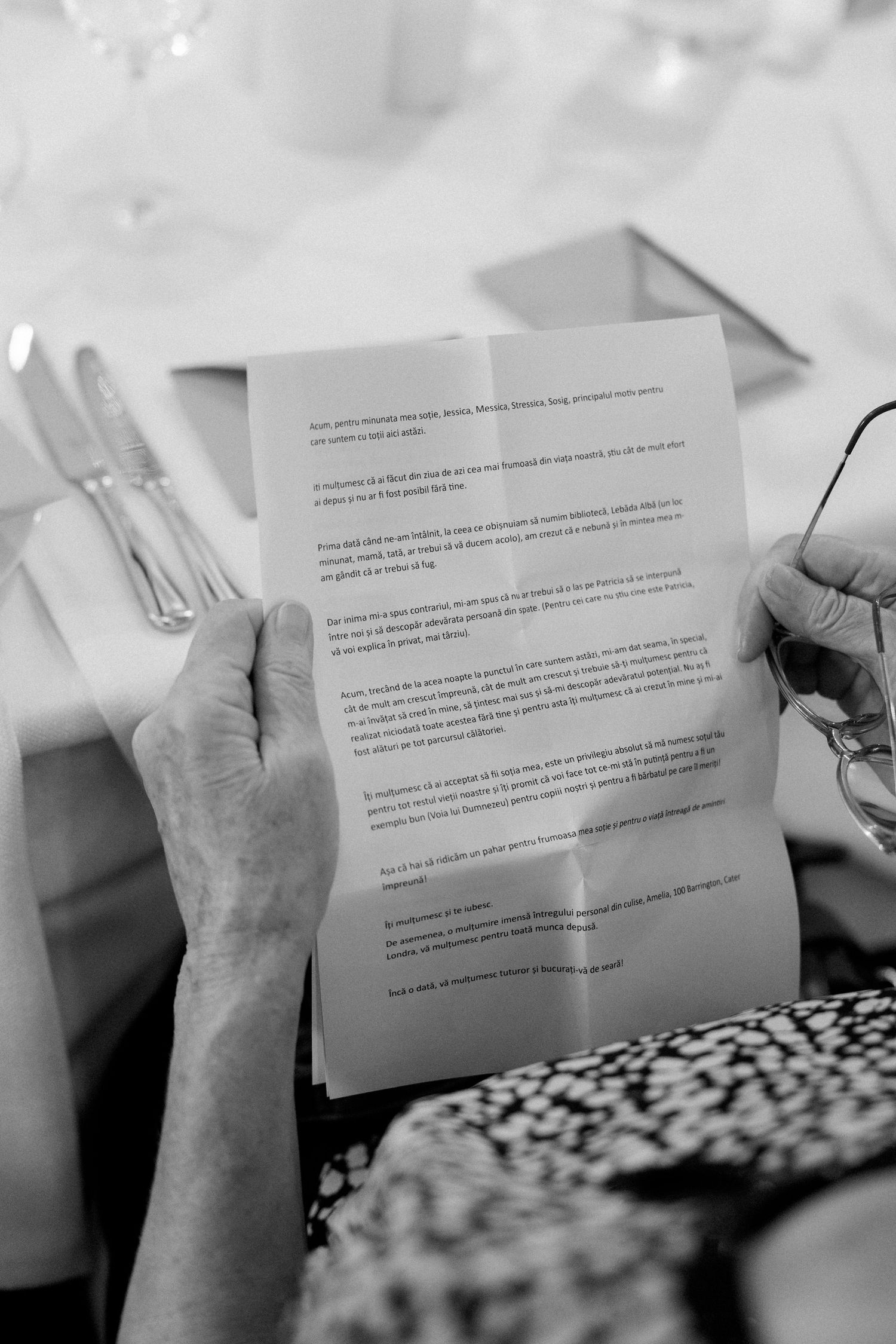 Black and white image of hands holding wedding ceremony reading papers during the service.