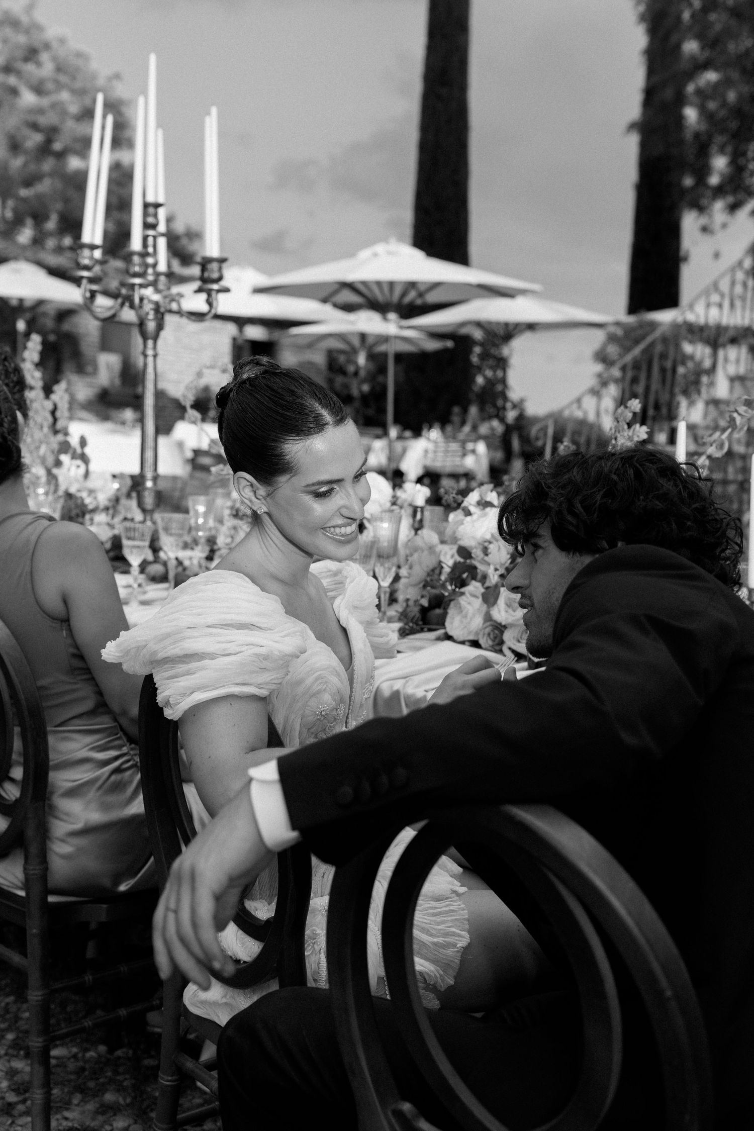 Wedding reception guests enjoying conversation at an outdoor dining table.